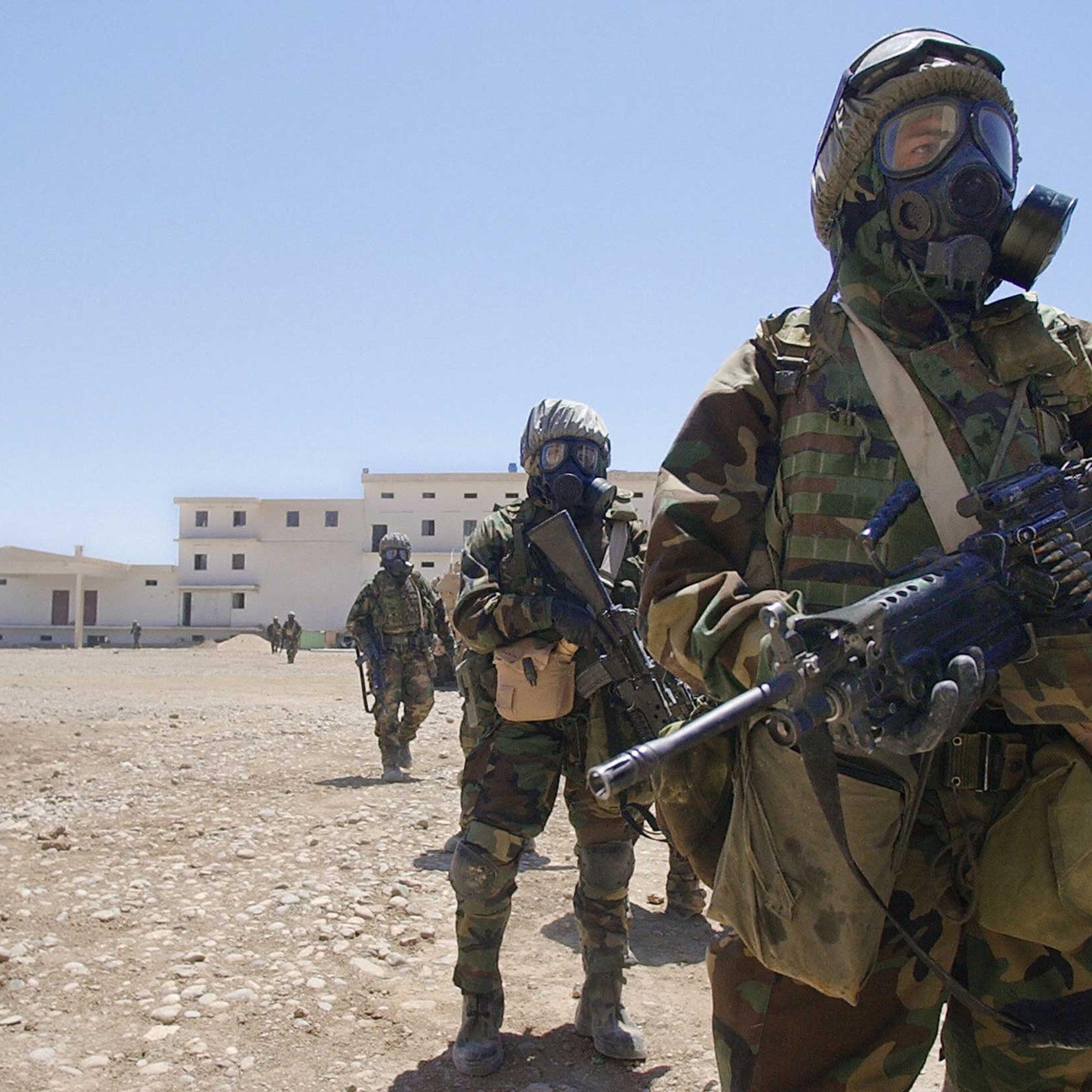 US Army soldiers wearing their full chemical protection suits walk inside the courtyard of an industrial complex they secured which they thought was a possible site for weapons of mass destruction in the central Iraqi town of Baquba in May 2003.