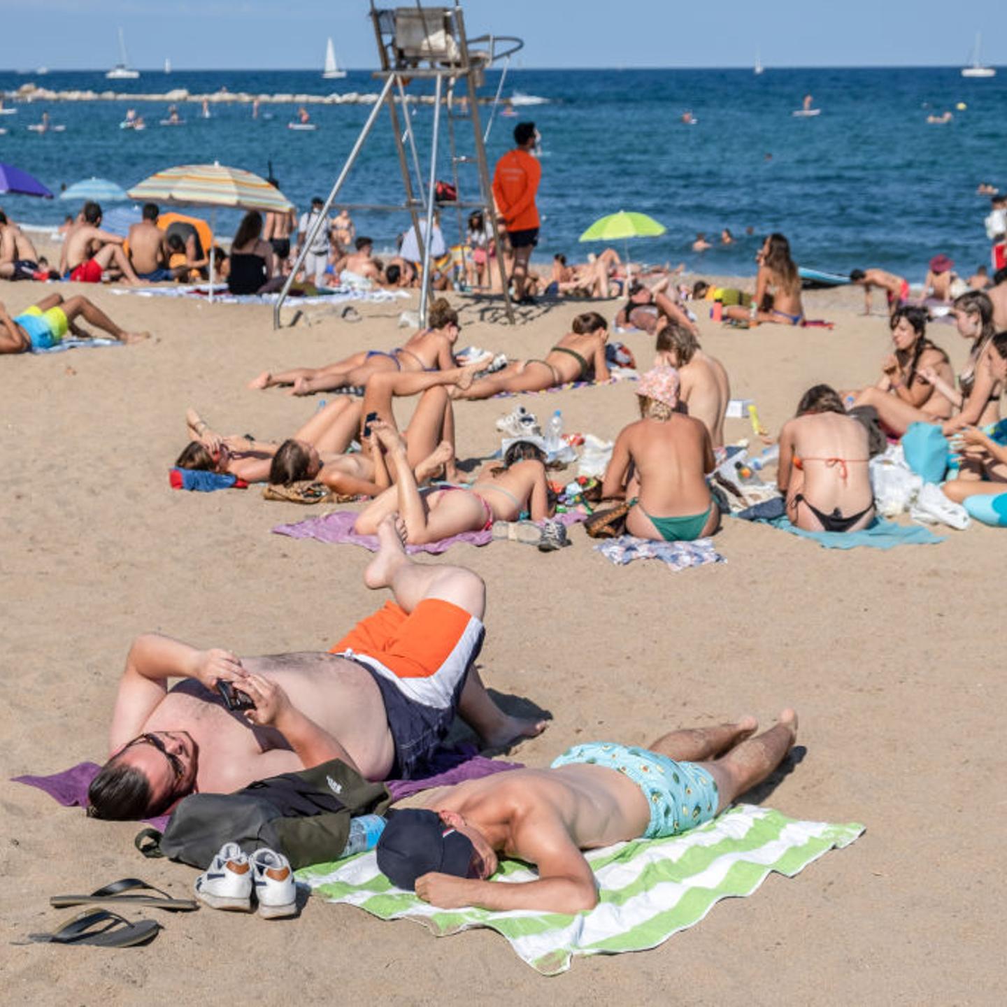 People are seen sunbathing at the Barceloneta beach during