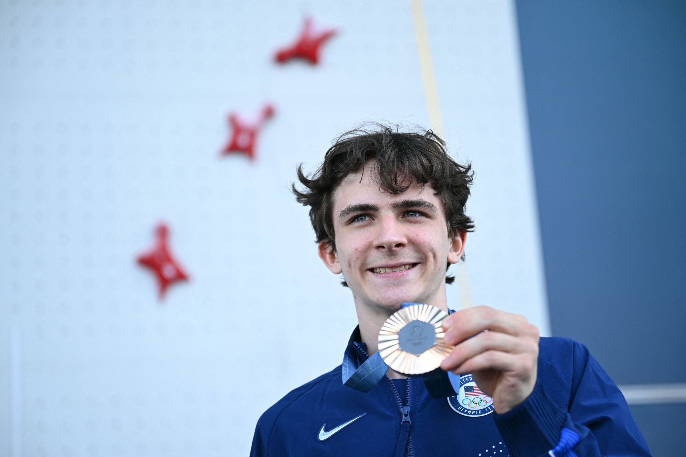 Bronze medalist Sam Watson poses on the podium of the men’s sport climbing speed event during the Paris 2024 Olympic Games on August 8, 2024.