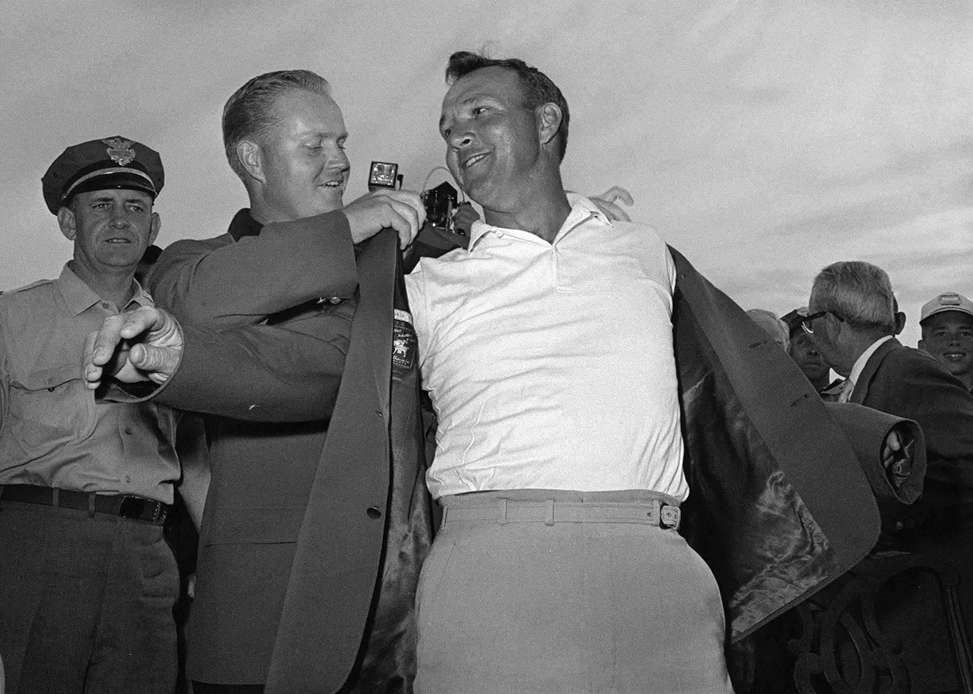 In this April 12, 1964 file photo, Arnold Palmer, slips into his green jacket with help from Jack Nicklaus after winning the Masters golf championship, in Augusta, Ga. 