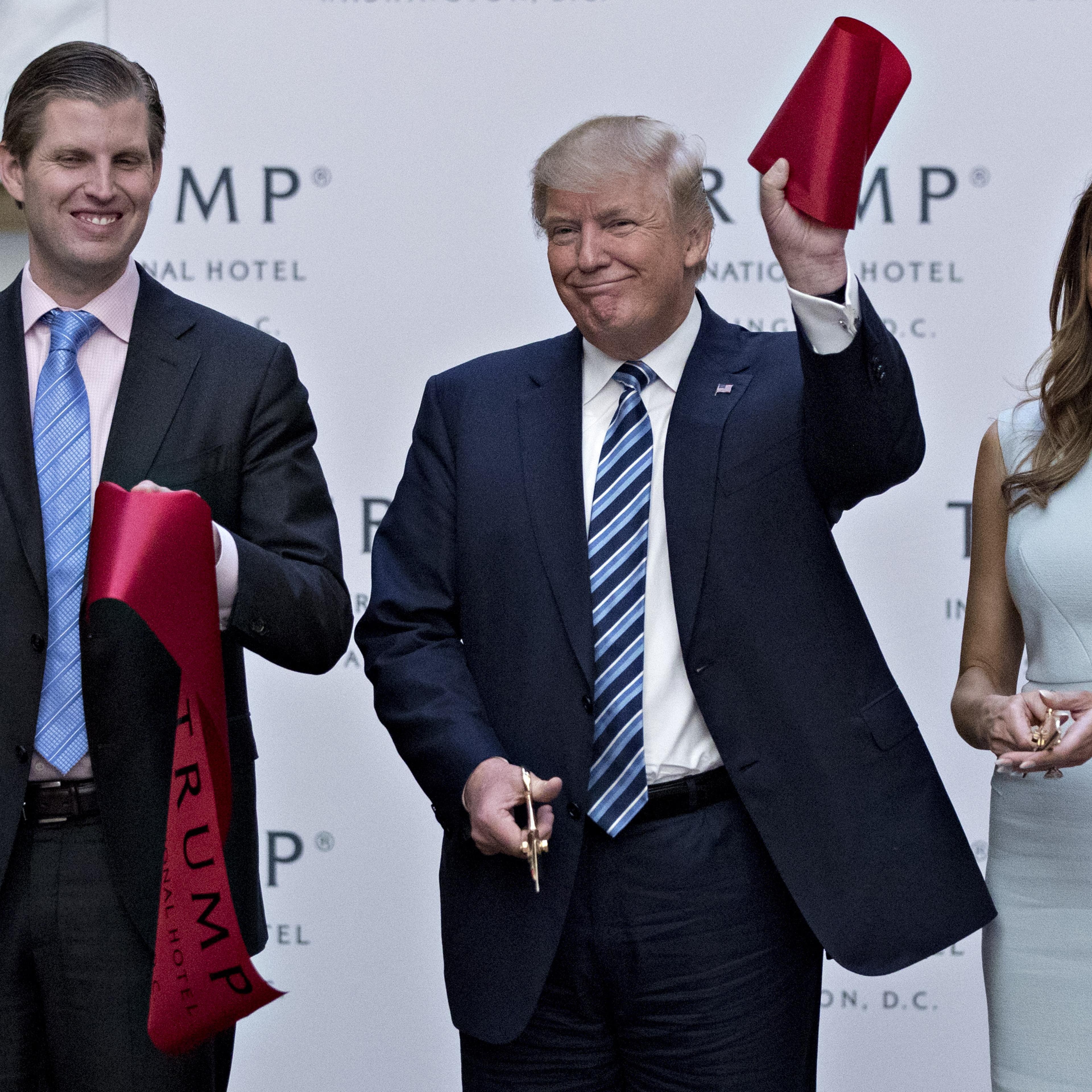 Donald Trump holds a piece of ribbon next to his wife Melania Trump, right, and his son Eric Trump during the grand opening ceremony of the Trump International Hotel in Washington, D.C., U.S., on Wednesday, Oct. 26, 2016.