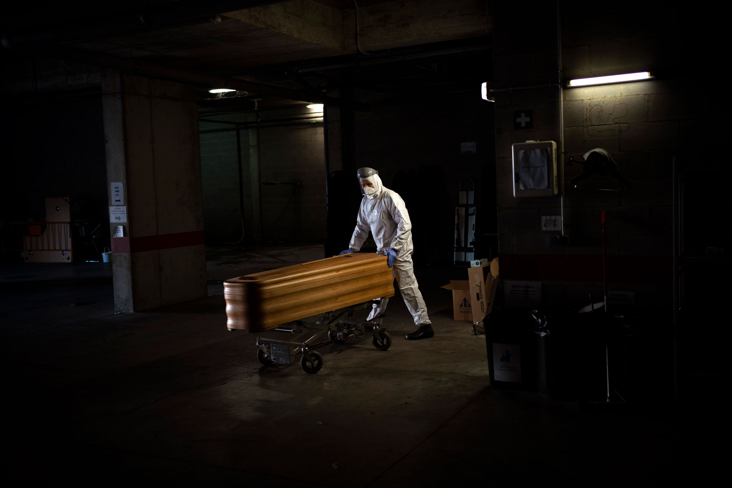 A mortuary worker moves a coffin carrying the body of a person who died of COVID-19