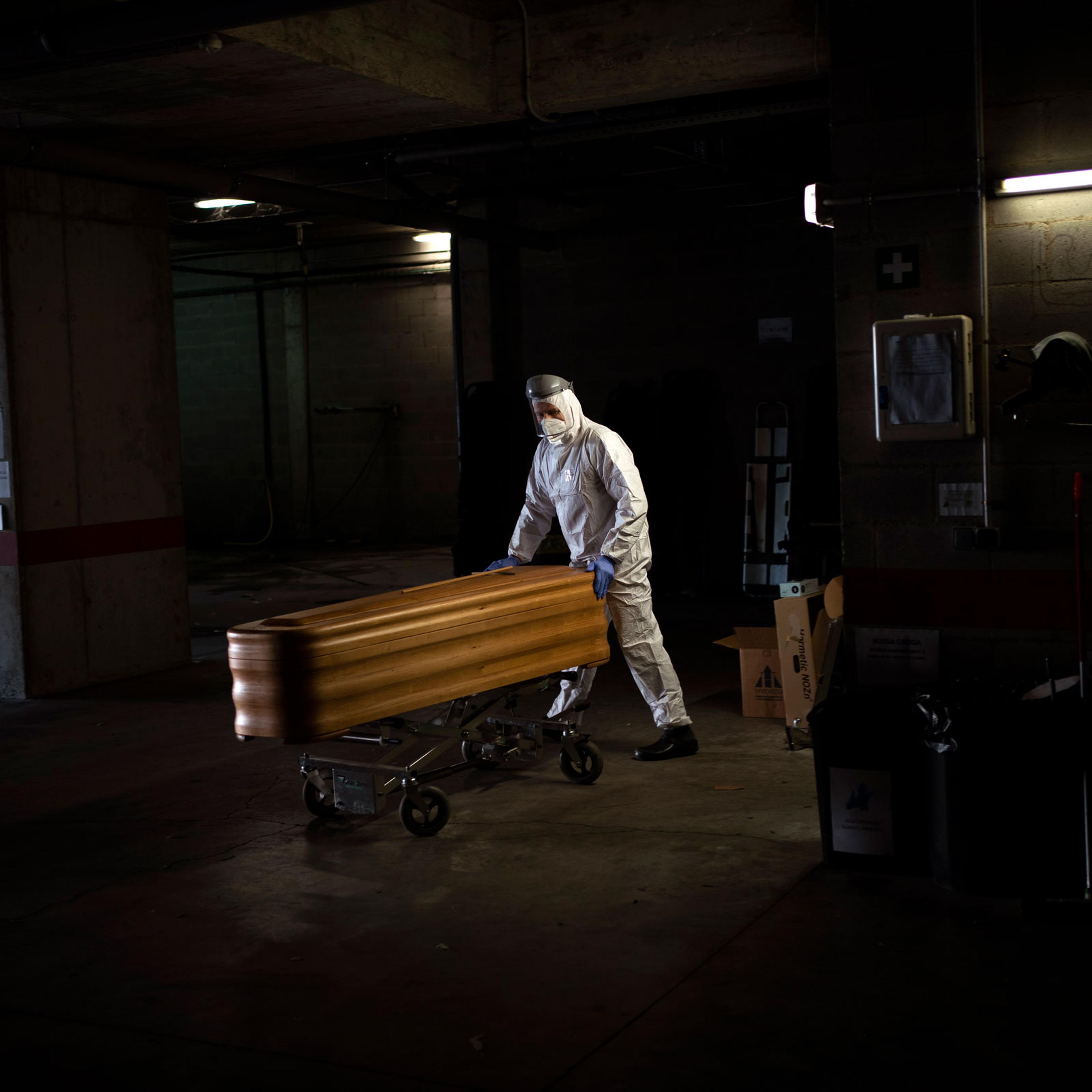 A mortuary worker moves a coffin carrying the body of a person who died of COVID-19