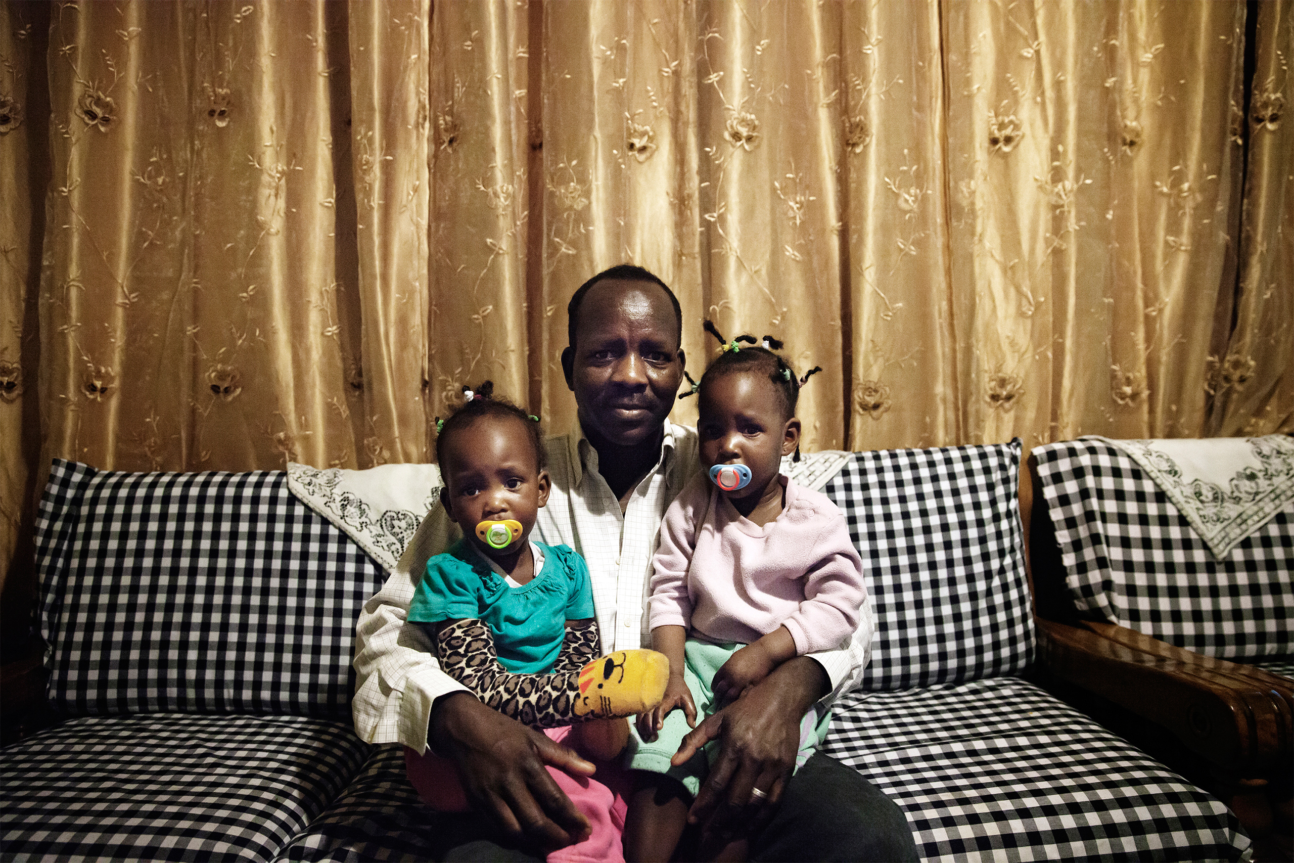 Boshora Adam, an African refugee, appears with his twin daughters in their home in Tel Aviv, Israel.  “The hardest part about raising my children in Israel is that it’s becoming more segregated," he says. "On the playground you notice that parents keep their children away from African children, and this worries me for my children’s future.”