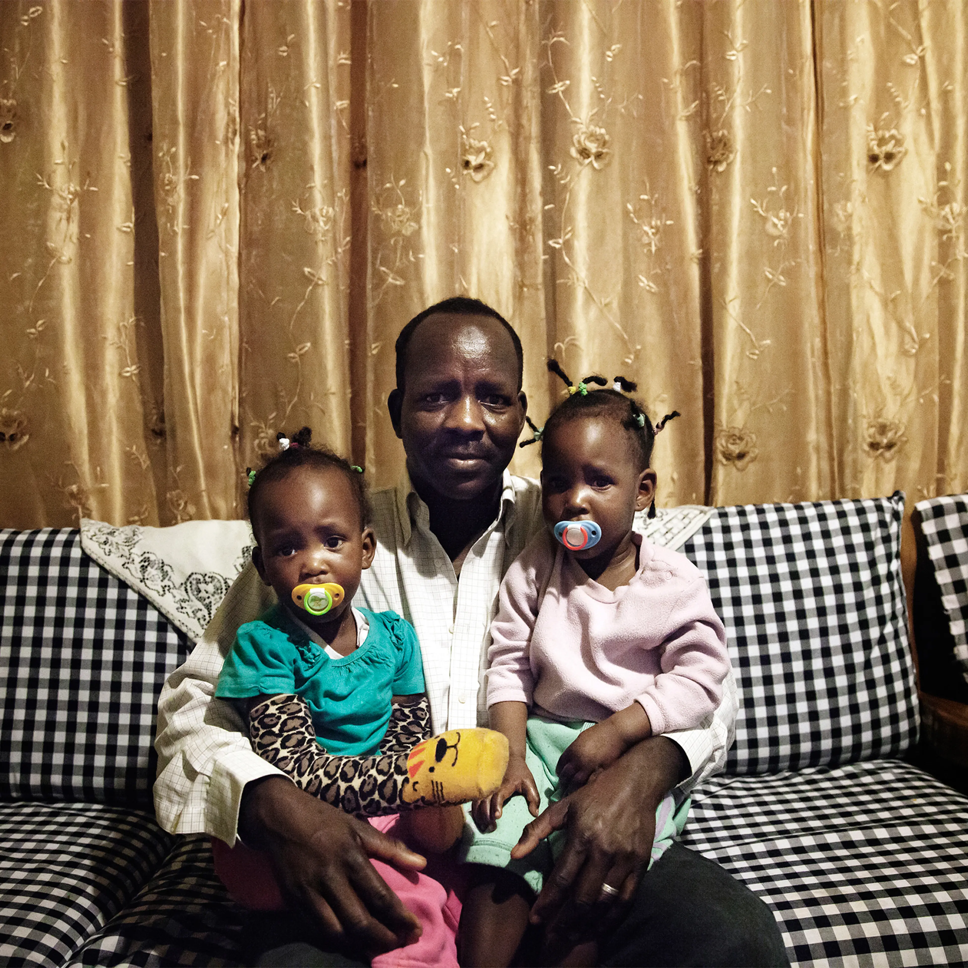 Boshora Adam, an African refugee, appears with his twin daughters in their home in Tel Aviv, Israel. “The hardest part about raising my children in Israel is that it’s becoming more segregated," he says. "On the playground you notice that parents keep their children away from African children, and this worries me for my children’s future.”
