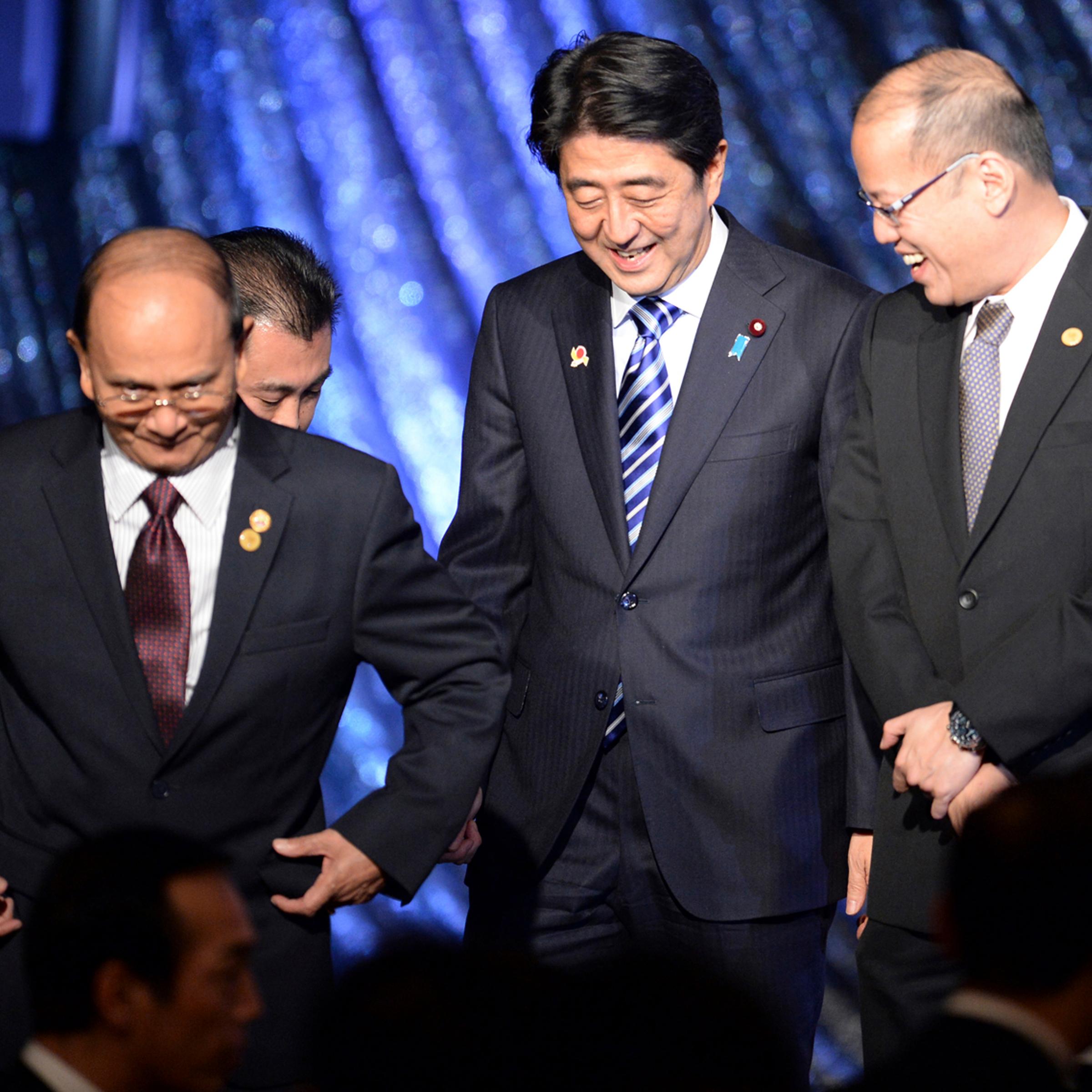 Japan's Prime Minister Shinzo Abe smiles with Myanmar's President Thein Sein and Philippine President Benigno Aquino as they leave the stage during a gala dinner of the ASEAN-Japan Commemorative Summit meeting in Tokyo
