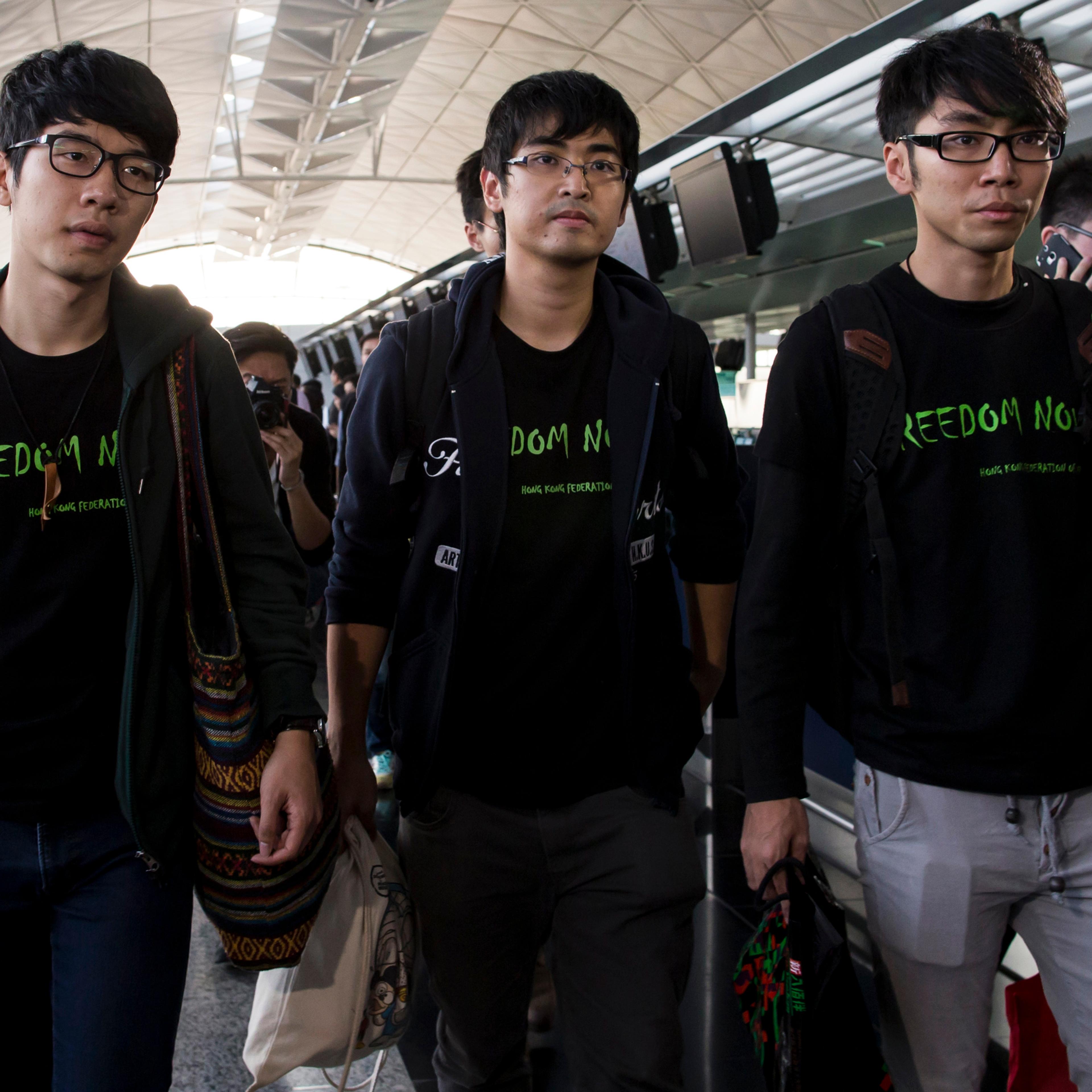 Hong Kong Federation of Students leader Alex Chow, committee members Nathan Law and Eason Chung react after being refused to board the plane at the Hong Kong International Airport