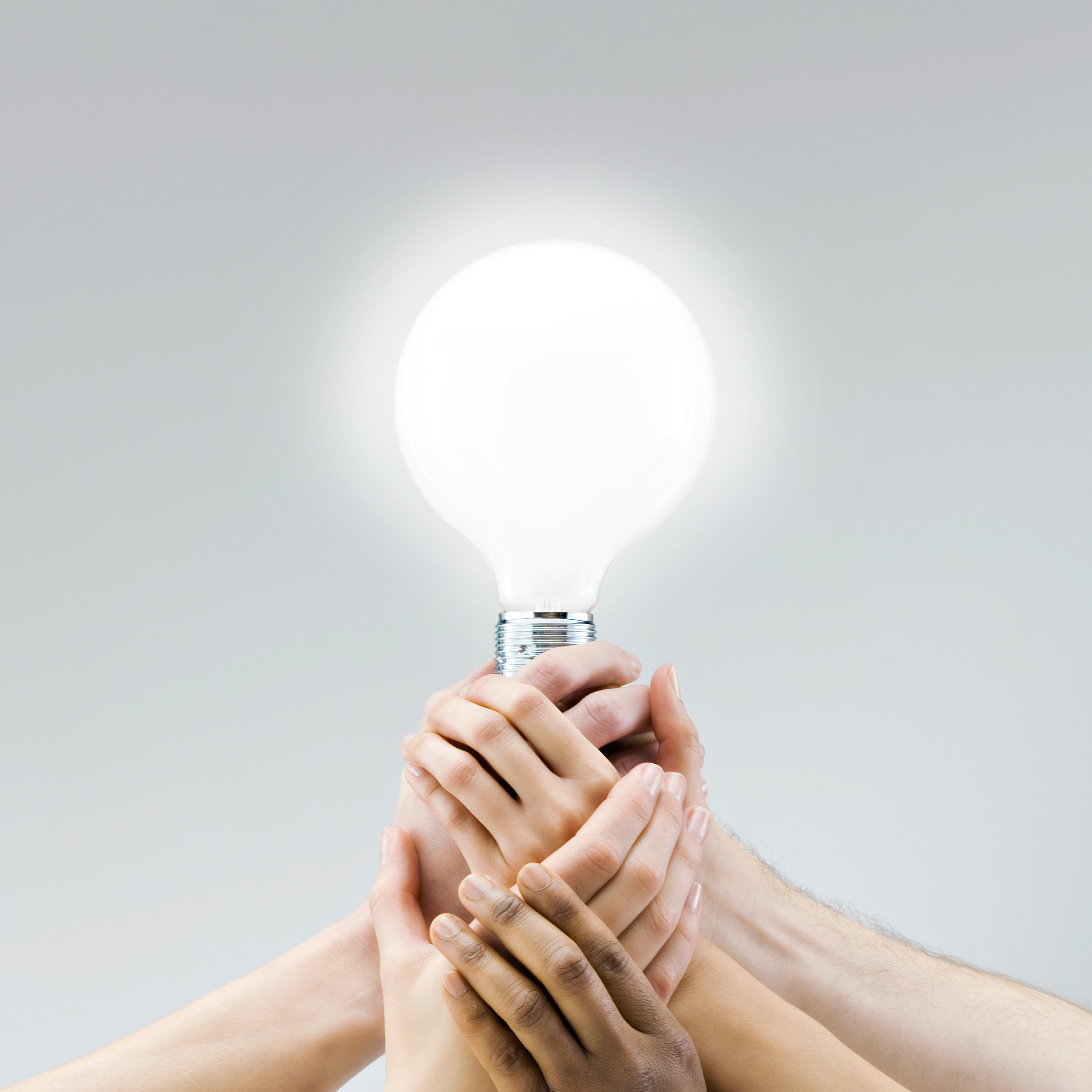 multiple hands holding lightbulb