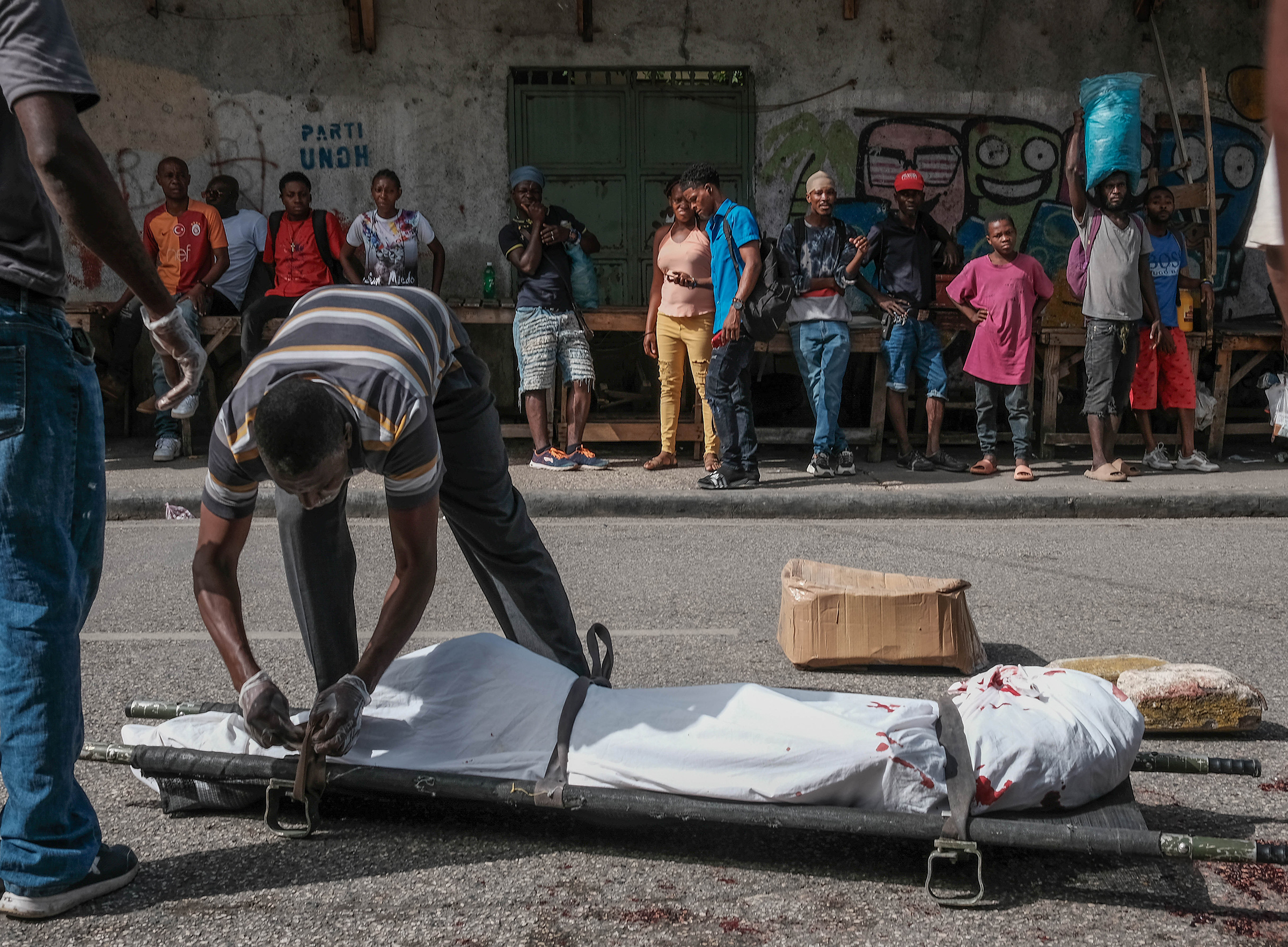 Police and forensics lift a body of a man killed in the streets in Port-Au-Prince, Haiti, on July 7, 2024.