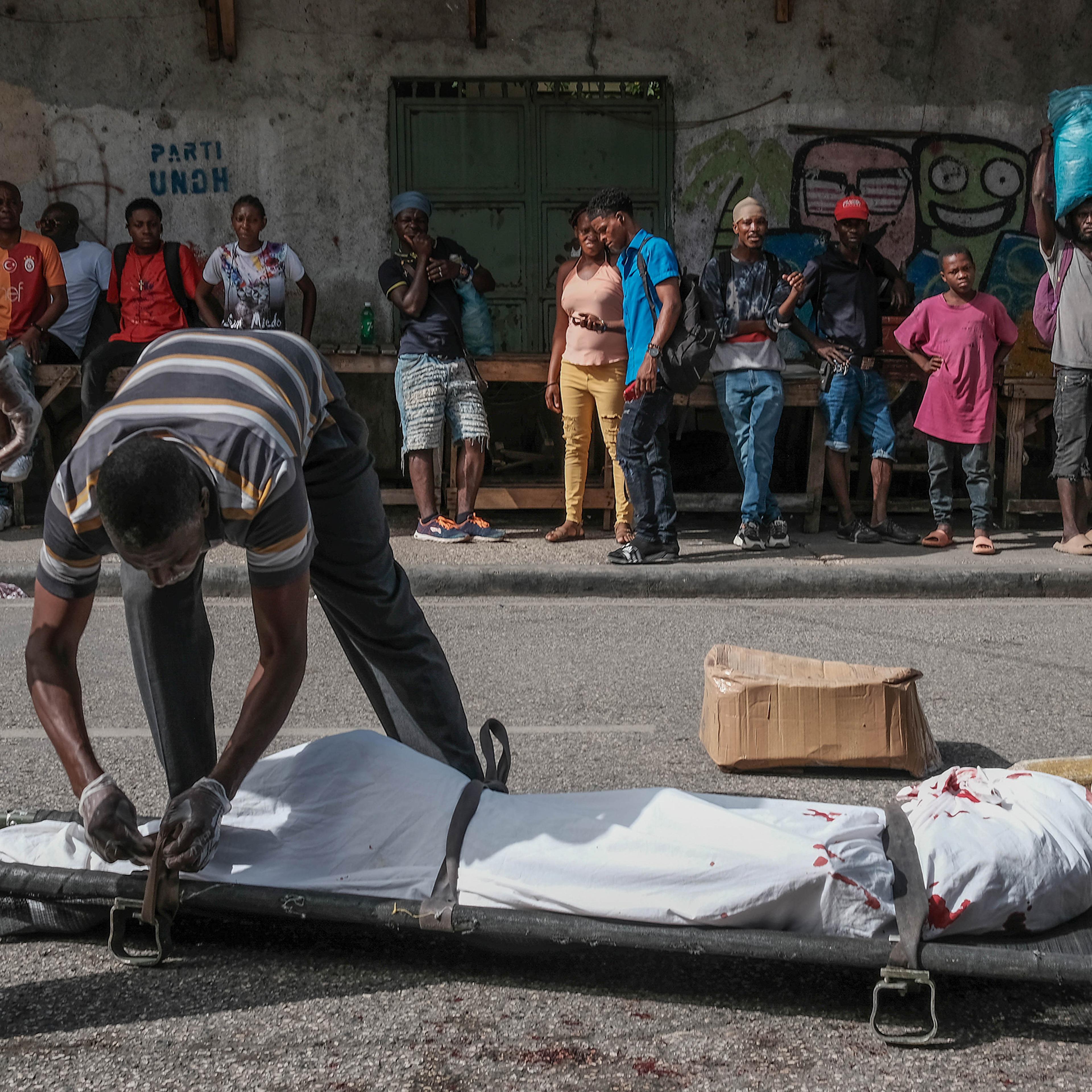 Police and forensics lift a body of a man killed in the streets in Port-Au-Prince, Haiti, on July 7, 2024.
