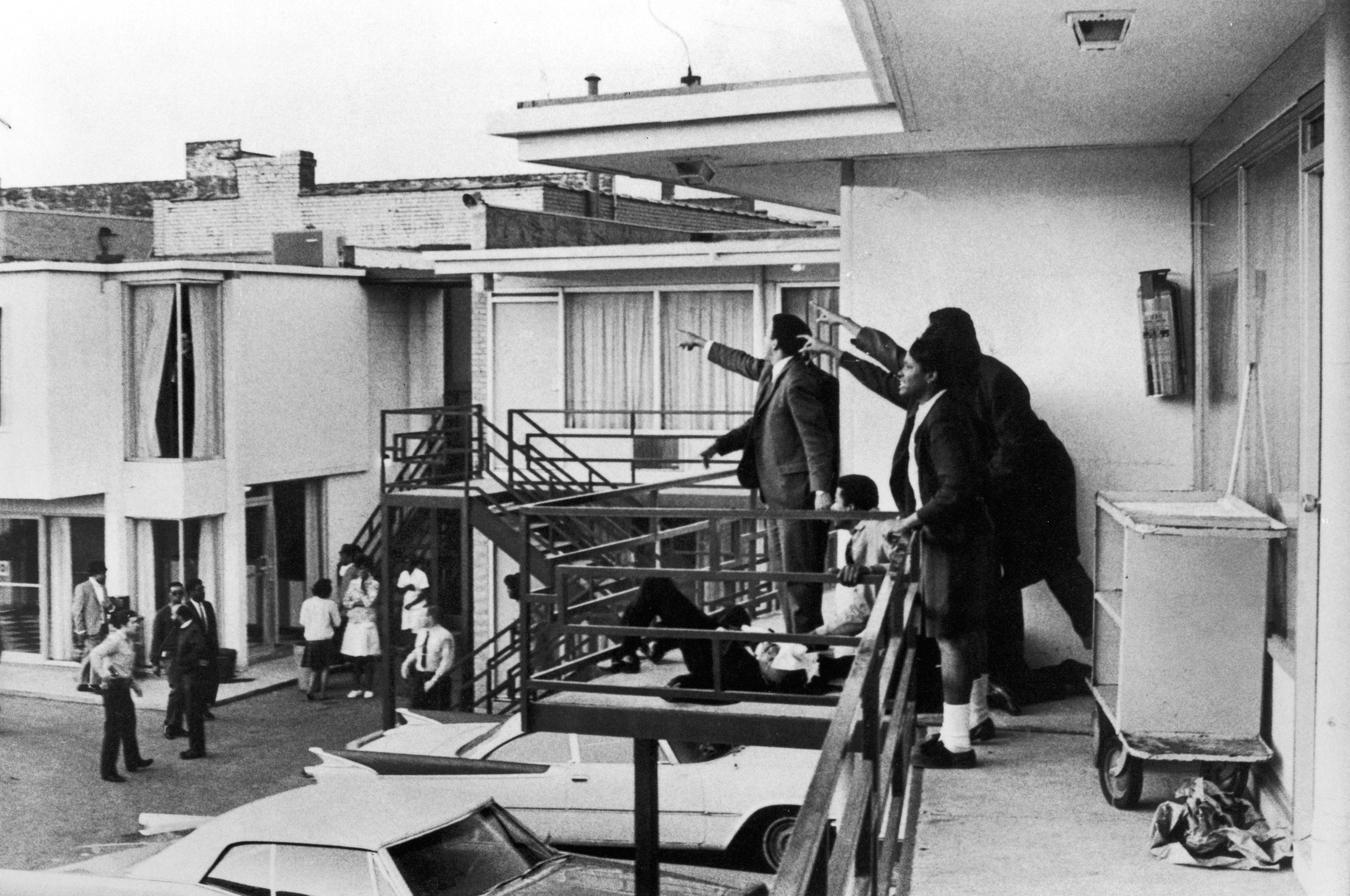 Civil rights leader Andrew Young (L) and others standing on balcony of Lorraine motel pointing in direction of assailant after assassination of civil rights ldr. Dr. Martin Luther King, Jr., who is lying at their feet.
