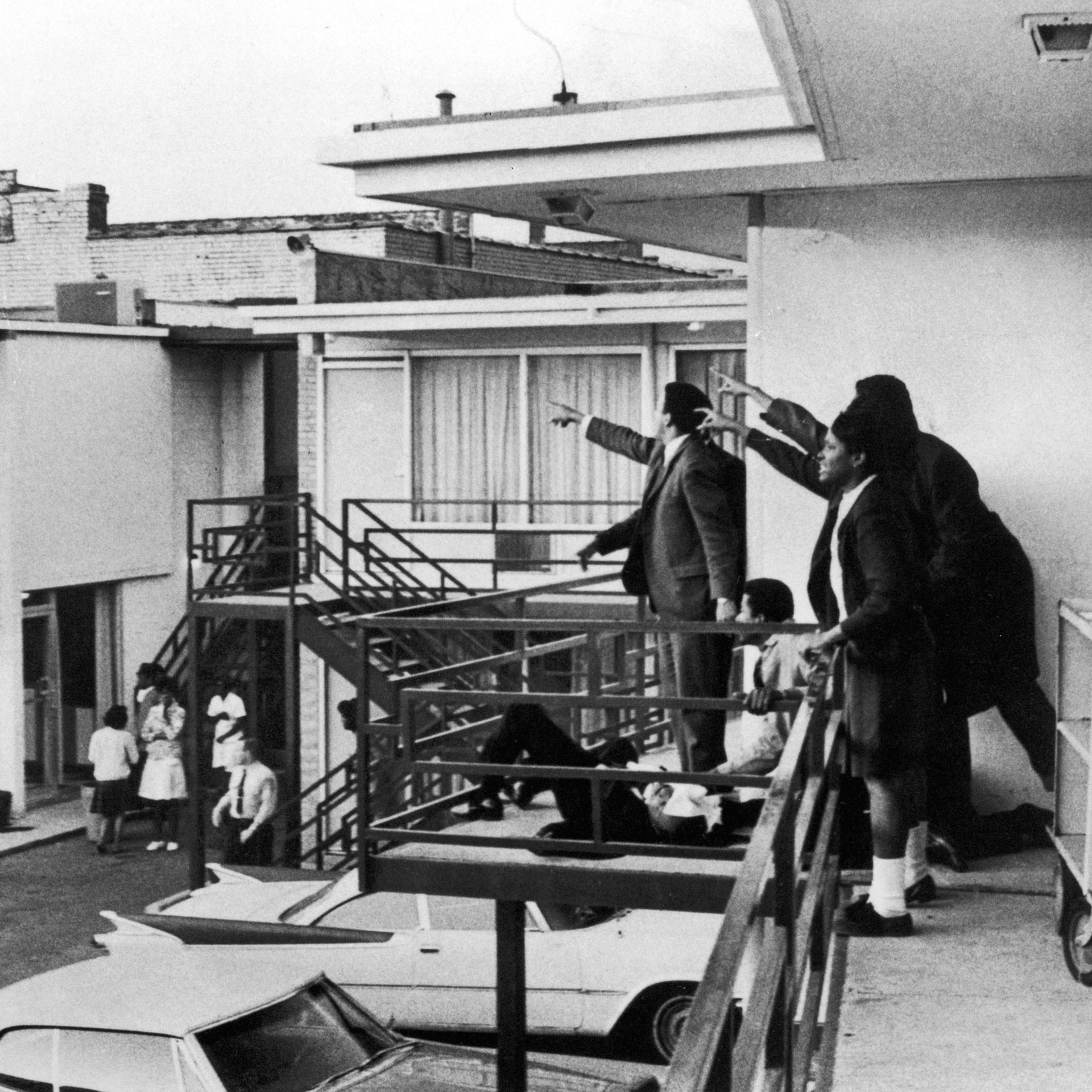 Civil rights leader Andrew Young (L) and others standing on balcony of Lorraine motel pointing in direction of assailant after assassination of civil rights ldr. Dr. Martin Luther King, Jr., who is lying at their feet.