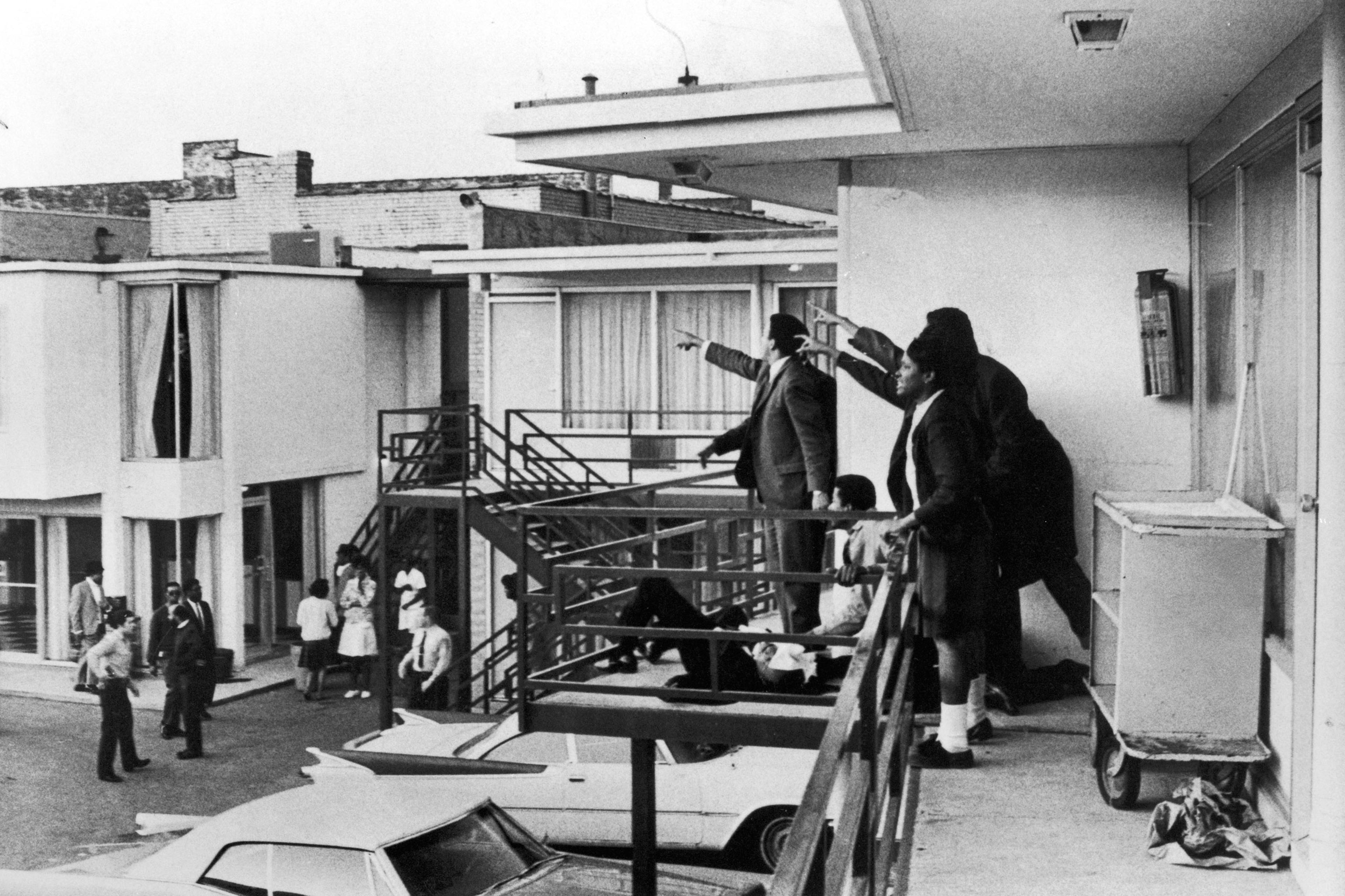 Civil rights leader Andrew Young (L) and others standing on balcony of Lorraine motel pointing in direction of assailant after assassination of civil rights ldr. Dr. Martin Luther King, Jr., who is lying at their feet.