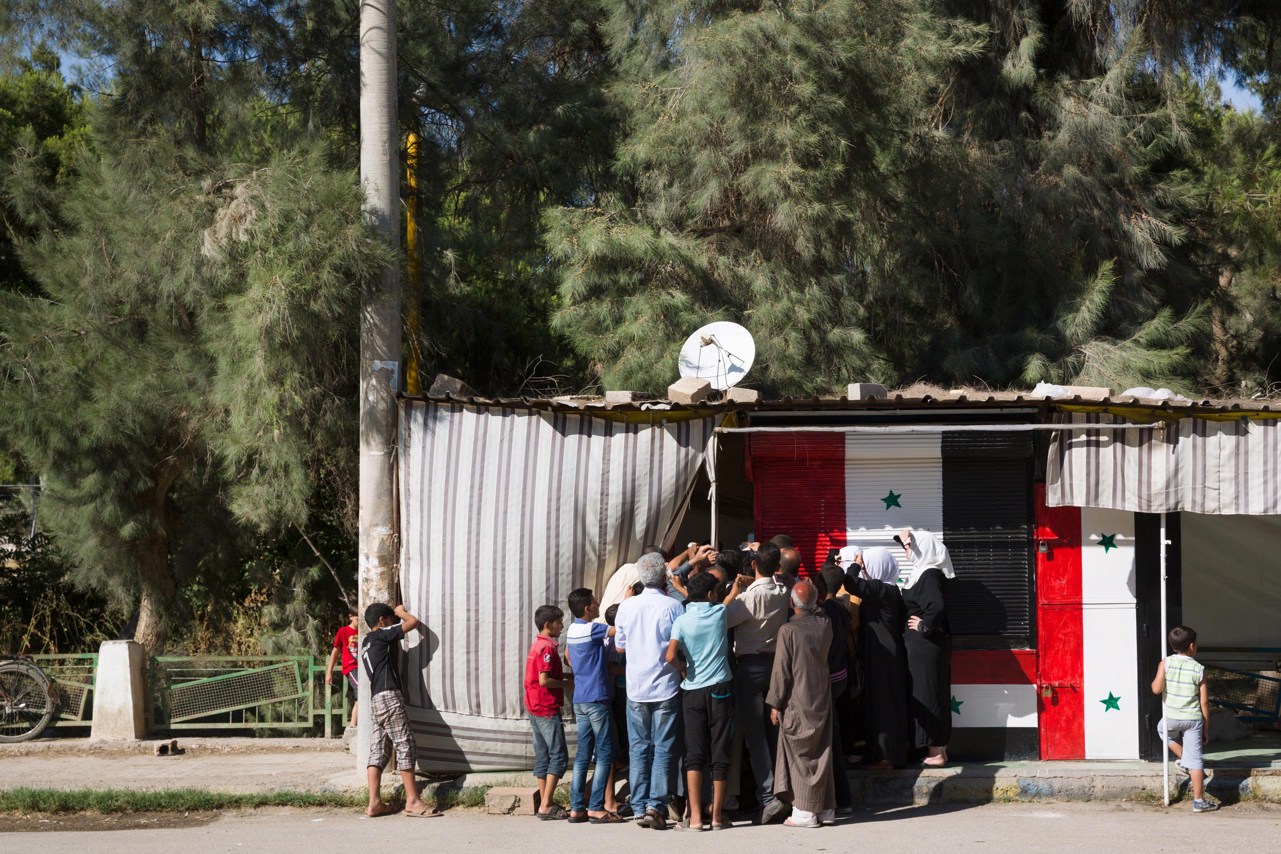 Residents often wait hours to buy bread provided by government-run bakeries because food is scarce. The Syrian government is struggling to retain normalcy in Deir-ez Zor, while fighting ISIS for control of the city, June 1, 2015.