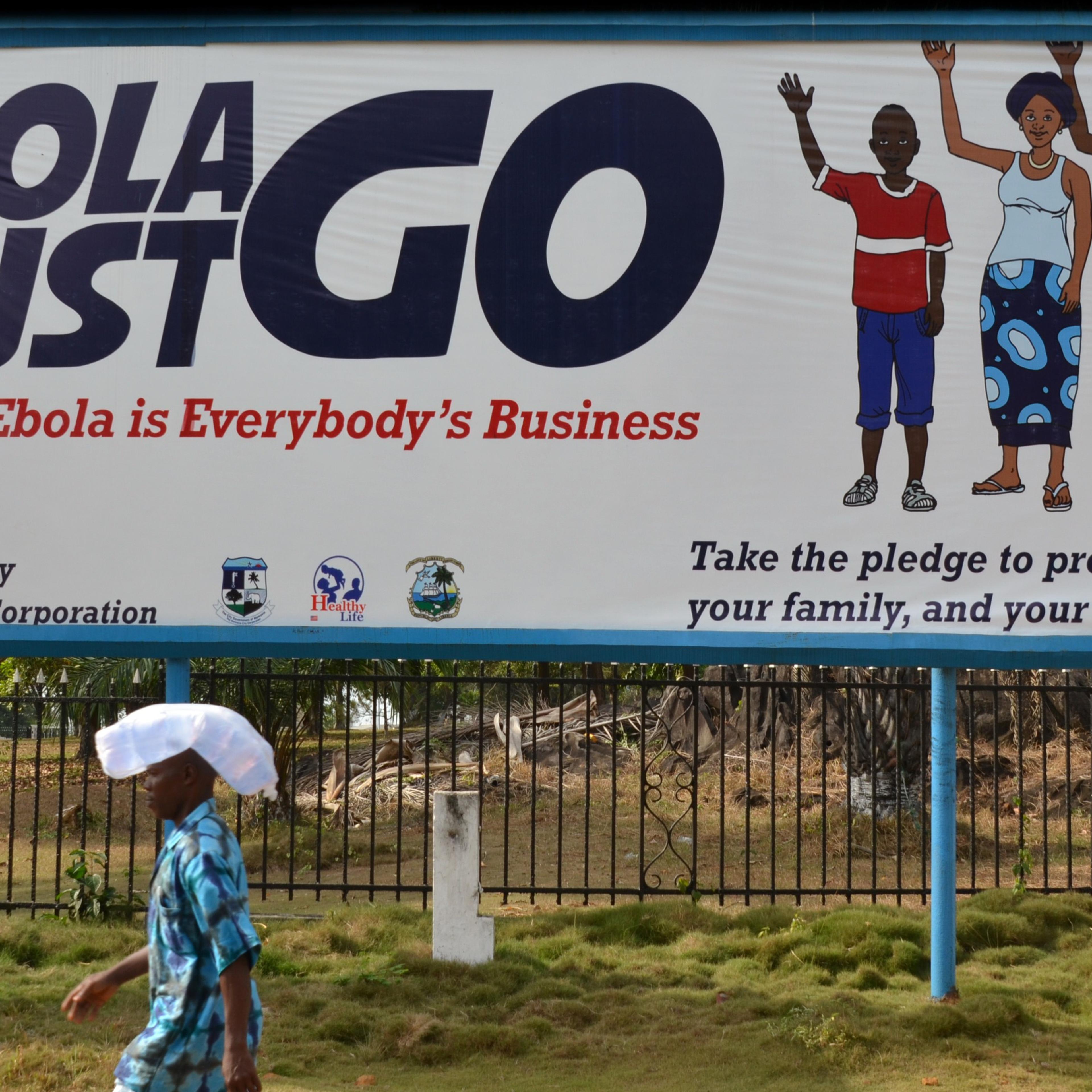 A man walks past an ebola campaign banner with the new slogan "Ebola Must GO" in Monrovia, Liberia on Feb. 23, 2015.