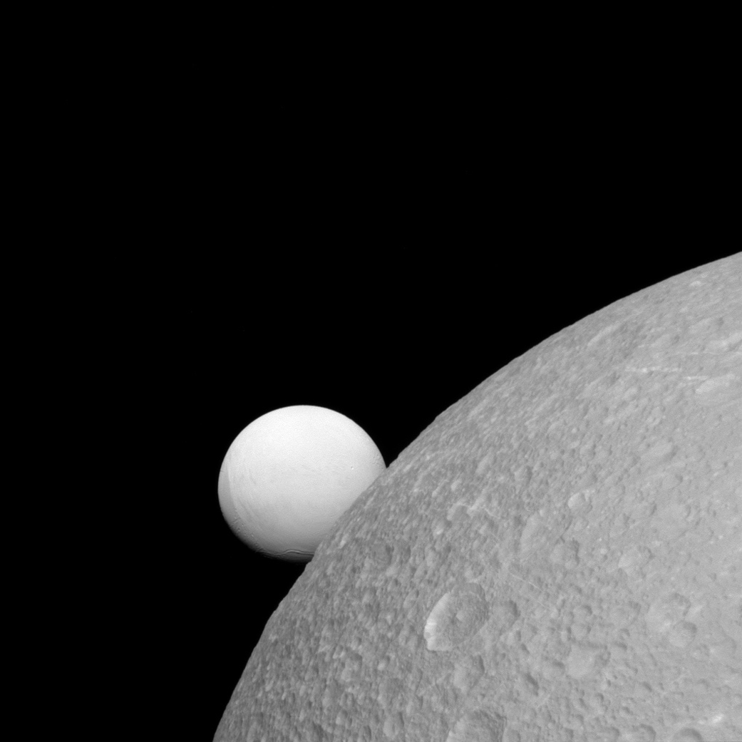 Although Dione (near) and Enceladus (far) are composed of nearly the same materials, Enceladus has a considerably higher reflectivity than Dione. As a result, it appears brighter against the dark night sky.This view looks toward the leading hemisphere of