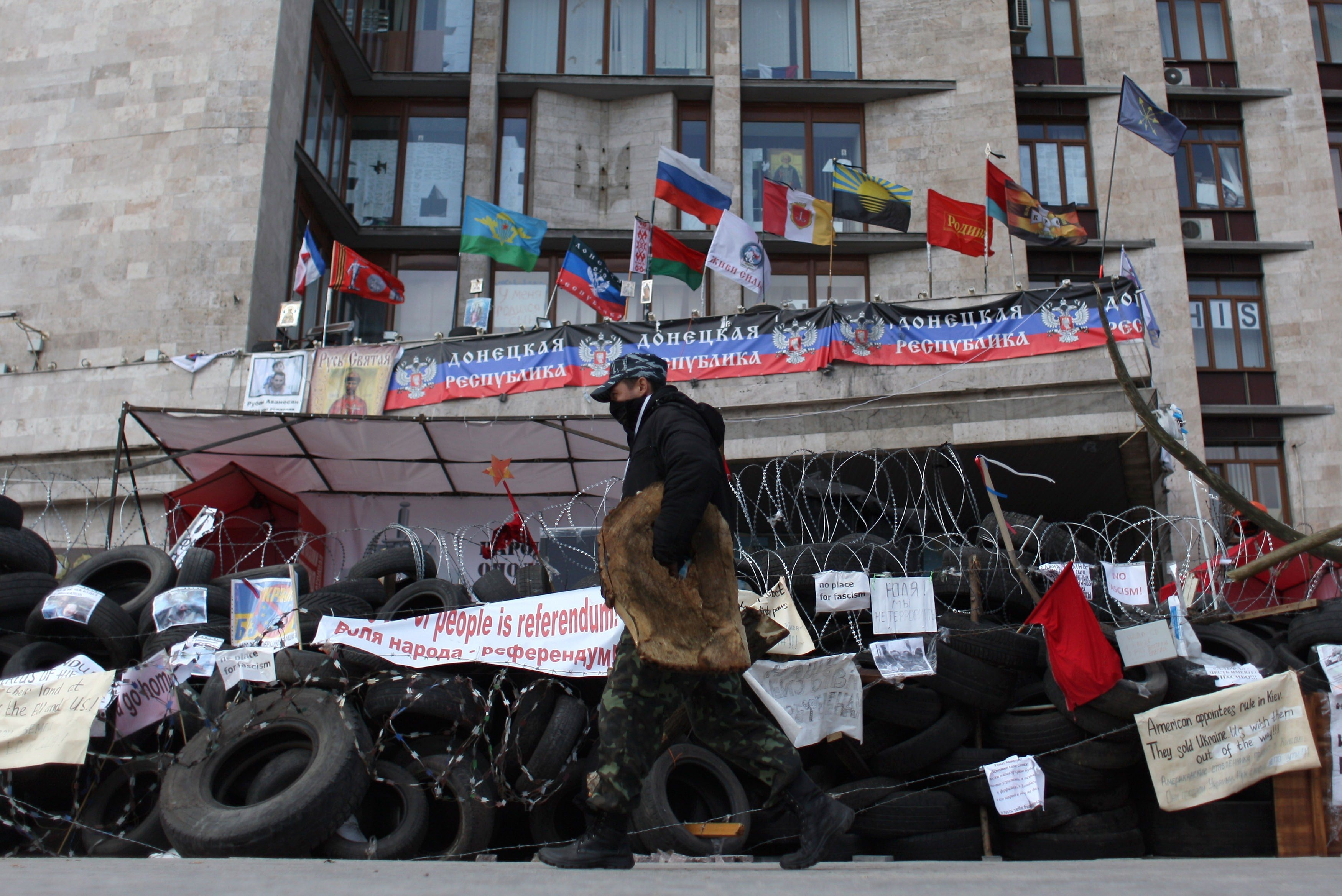 A pro-Russian activist walks in front a barricade set up outside the regional administrative building in the eastern Ukrainian city of Donetsk on April 21, 2014.