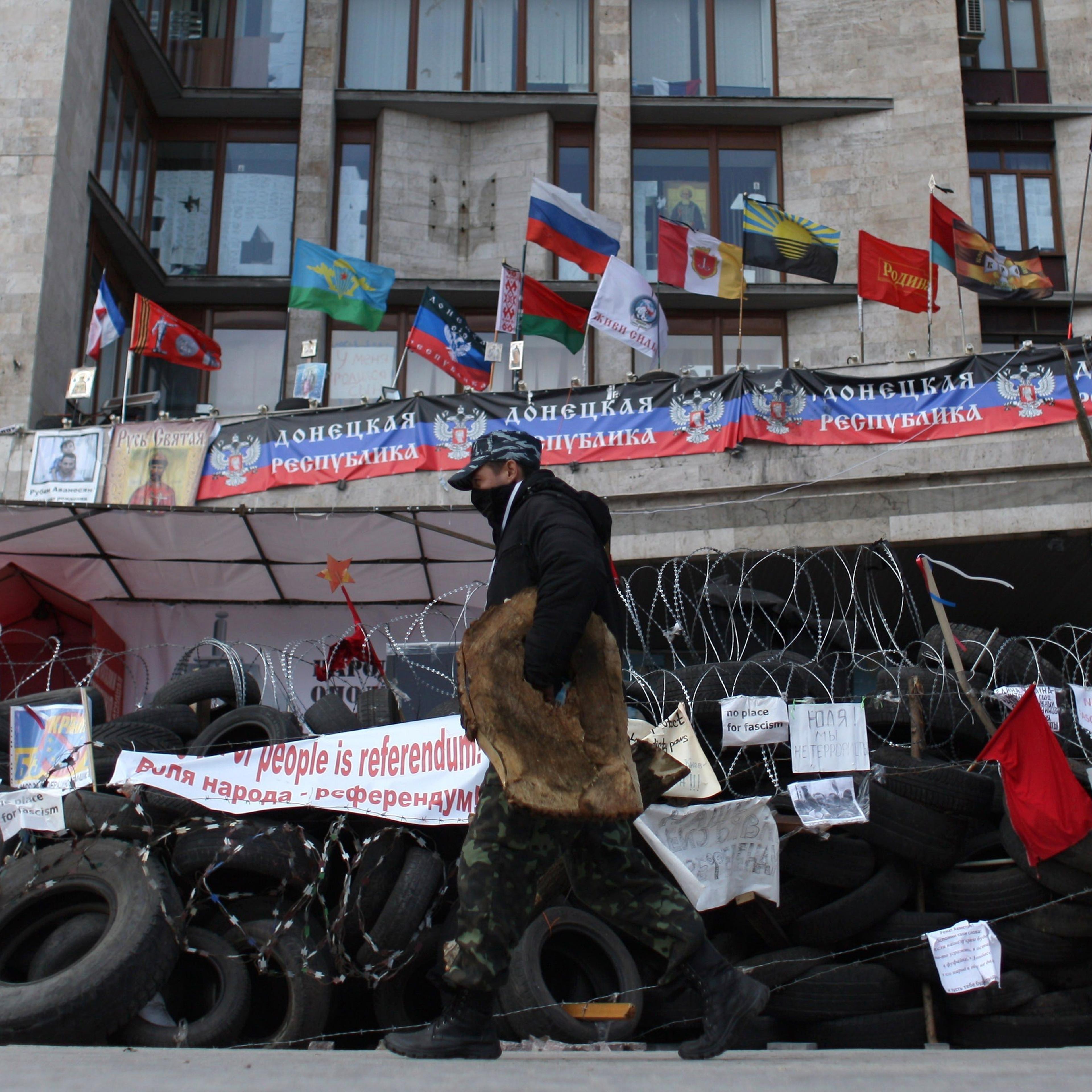 A pro-Russian activist walks in front a barricade set up outside the regional administrative building in the eastern Ukrainian city of Donetsk on April 21, 2014.