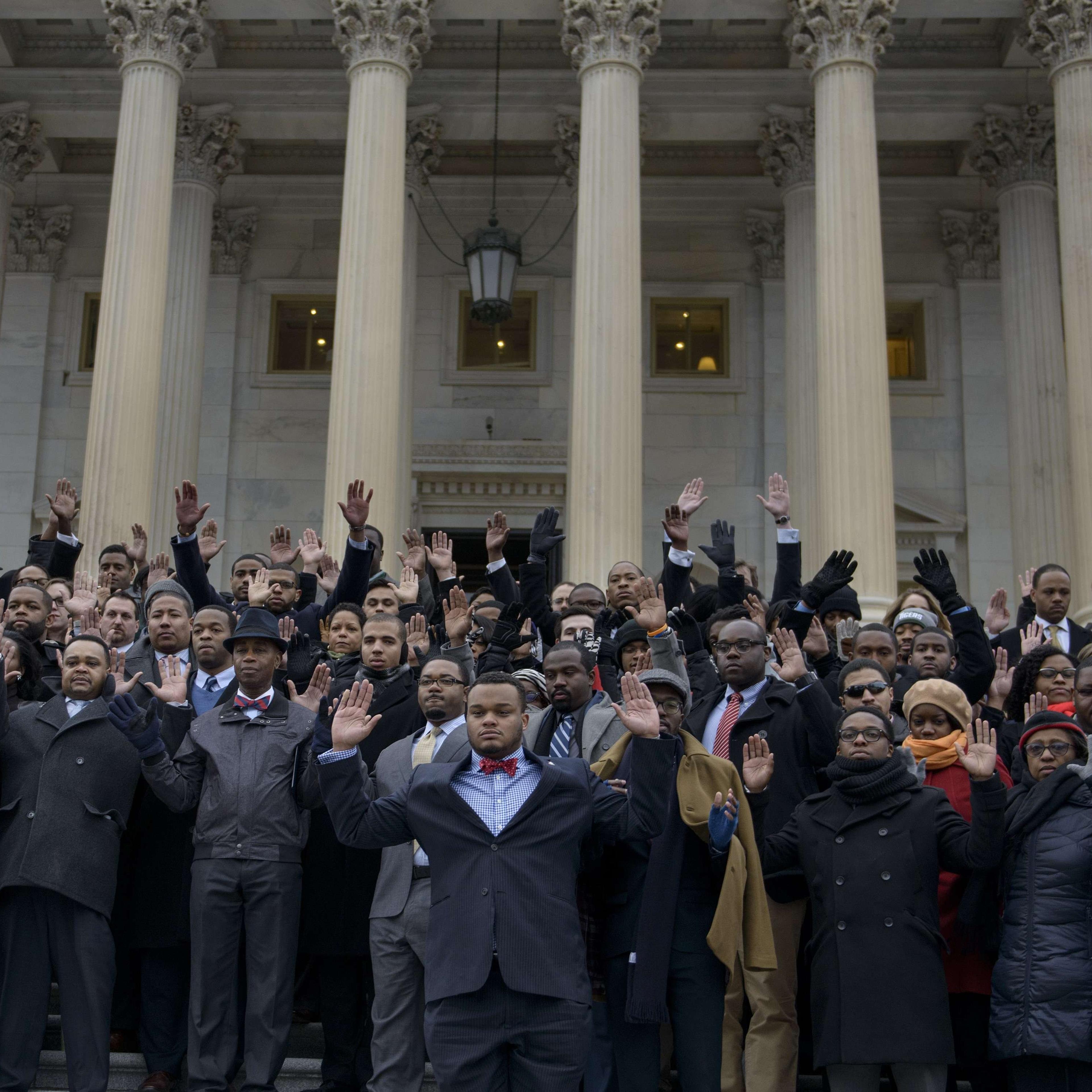 African-American Congressional staff and others hold their hands up during a walk-out outside the House on Capitol Hill on Dec. 11, 2014 in Washington D.C.