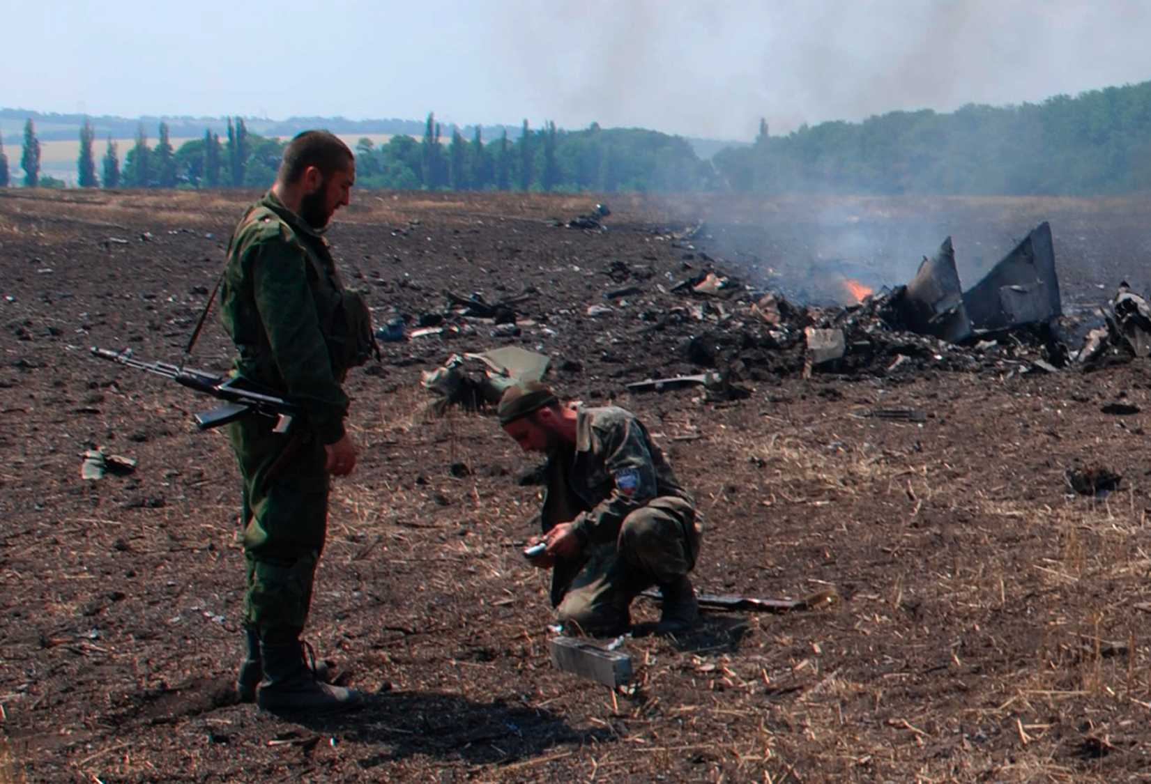 In this framegrab made from a video provided by press service of the rebel Donetsk People's Republic and icorpus.ru, pro-Russians collect parts of the burning debris of a Ukrainian military fighter jet, shot down at Savur Mogila, eastern Ukraine, Wednesday, July 23, 2014.
