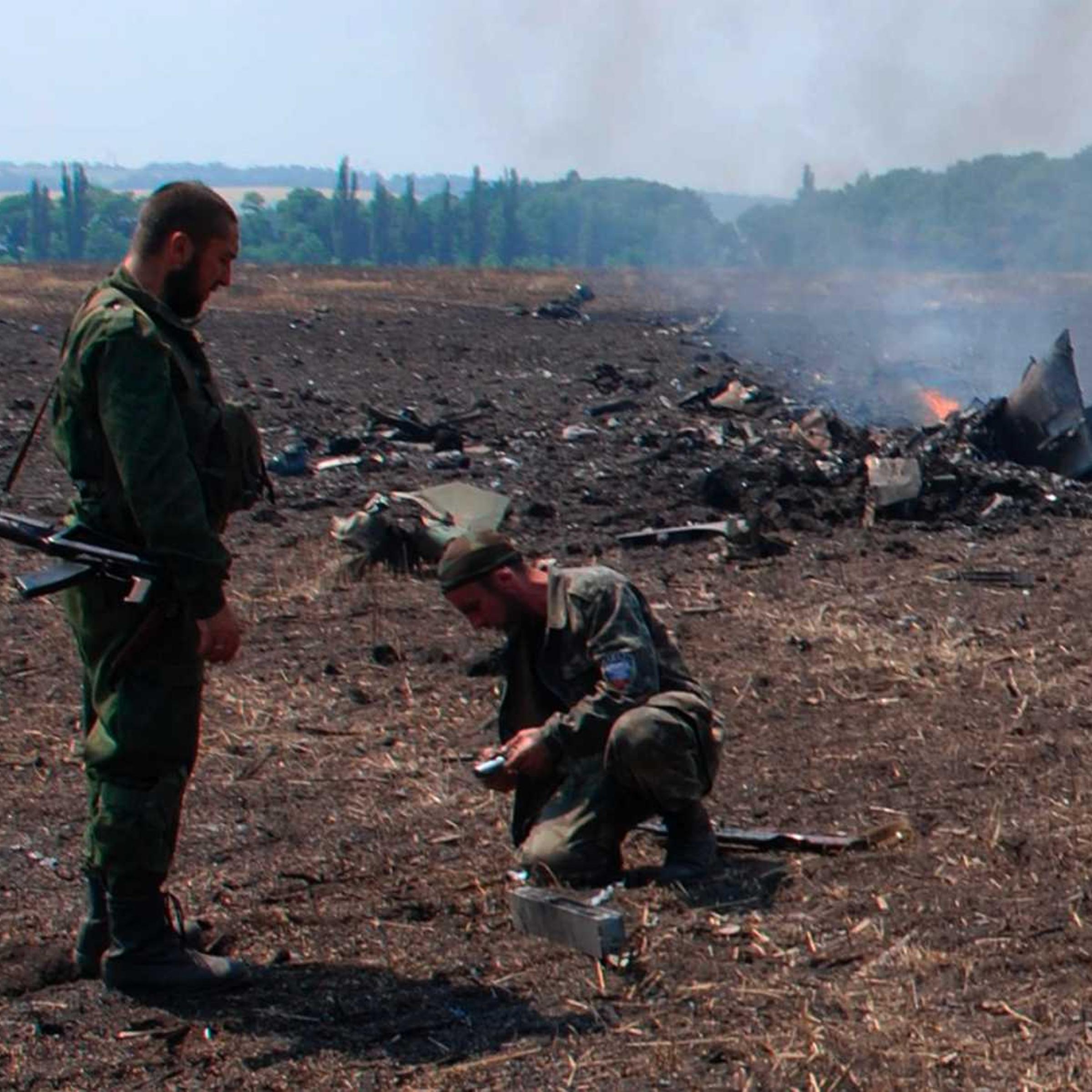 In this framegrab made from a video provided by press service of the rebel Donetsk People's Republic and icorpus.ru, pro-Russians collect parts of the burning debris of a Ukrainian military fighter jet, shot down at Savur Mogila, eastern Ukraine, Wednesday, July 23, 2014.