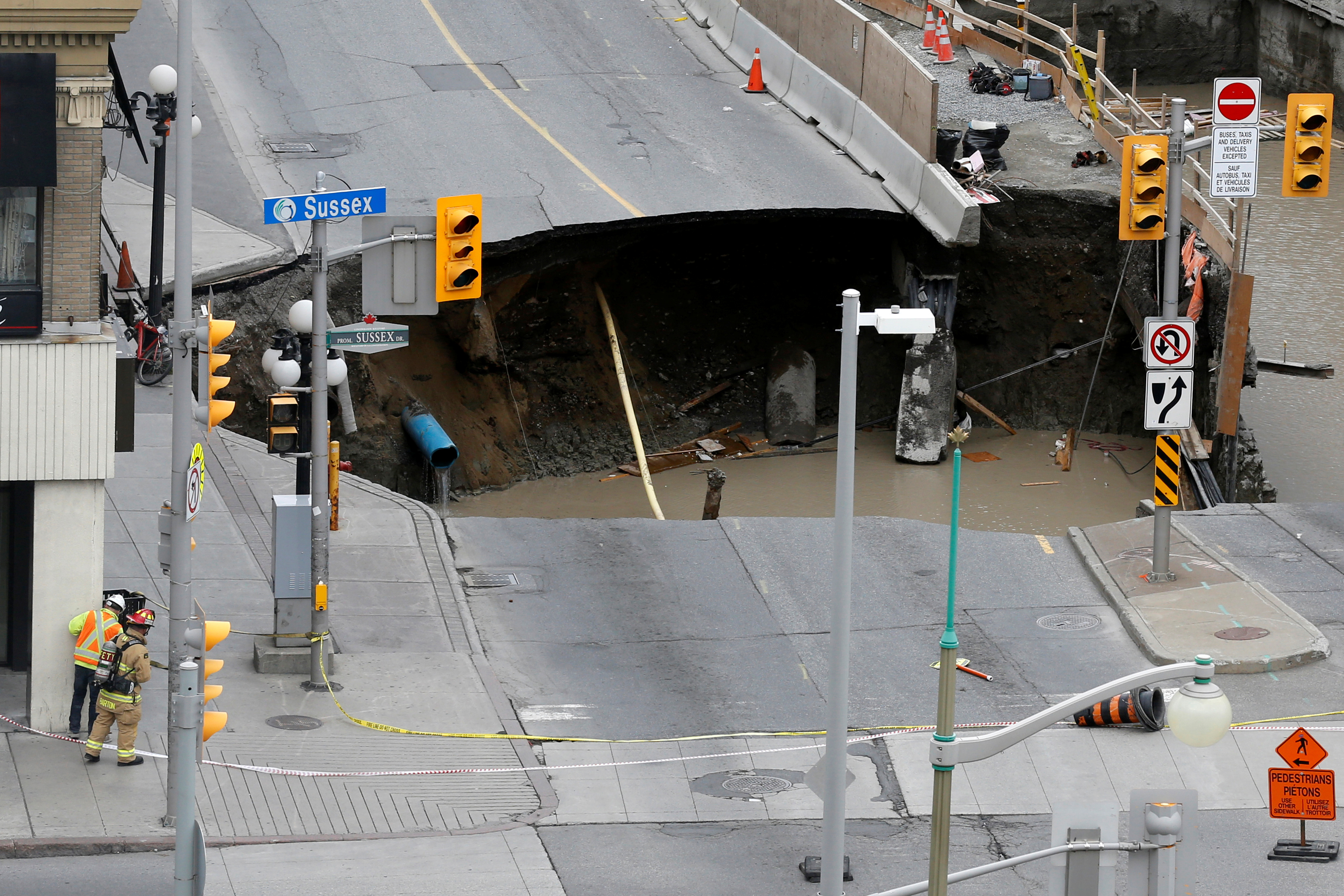 Workers look at a large sinkhole in Ottawa