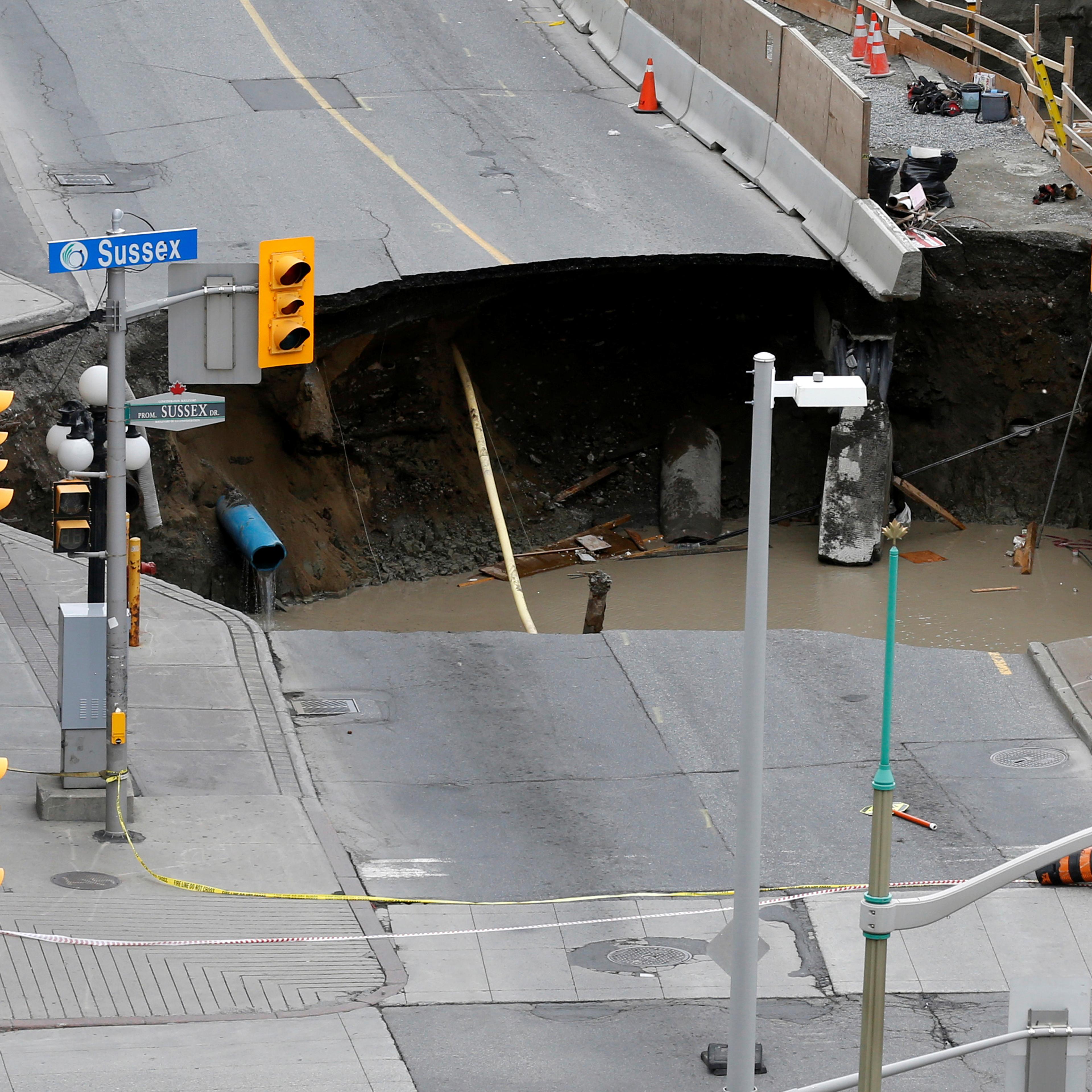 Workers look at a large sinkhole in Ottawa