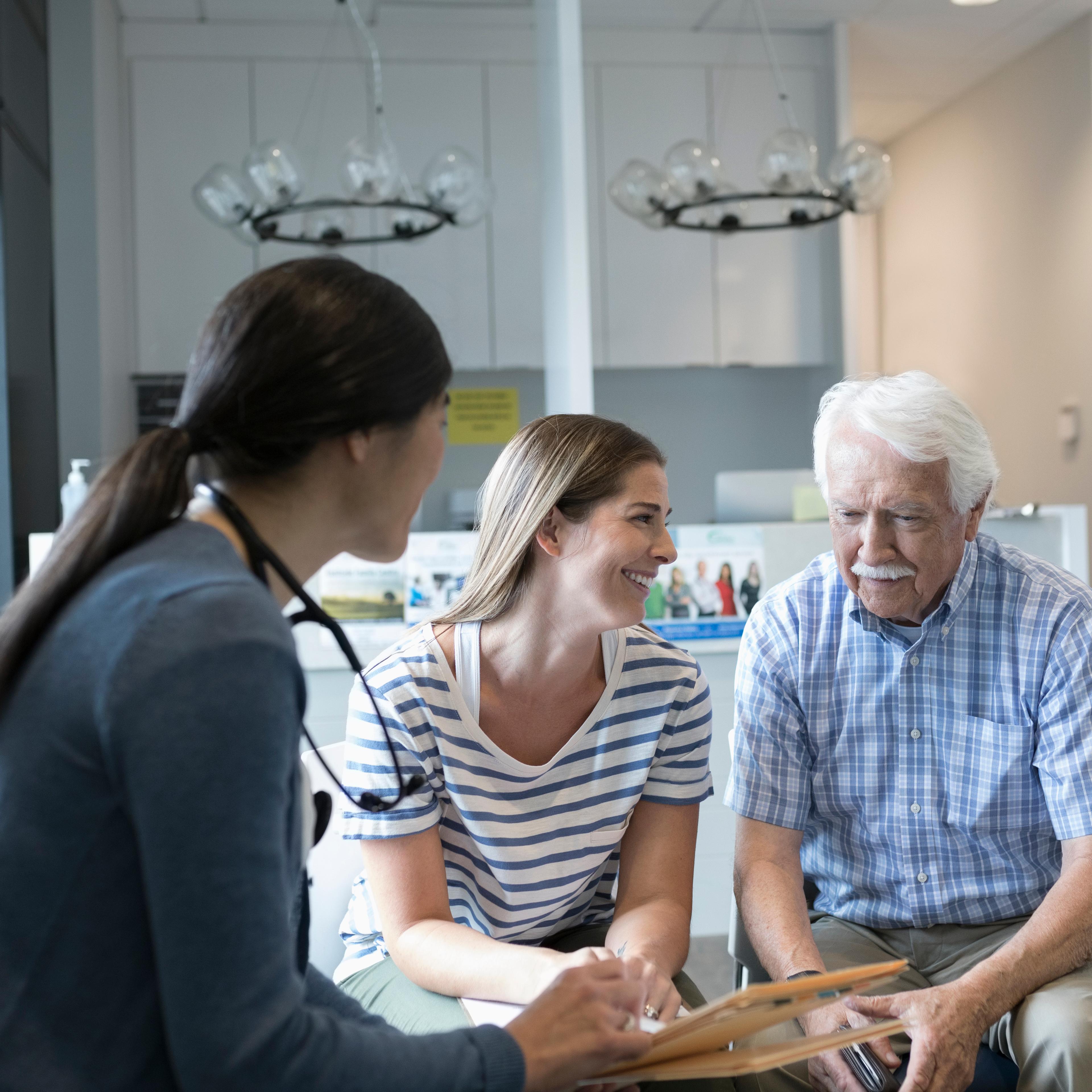 Female doctor talking with senior male patient in clinic waiting room