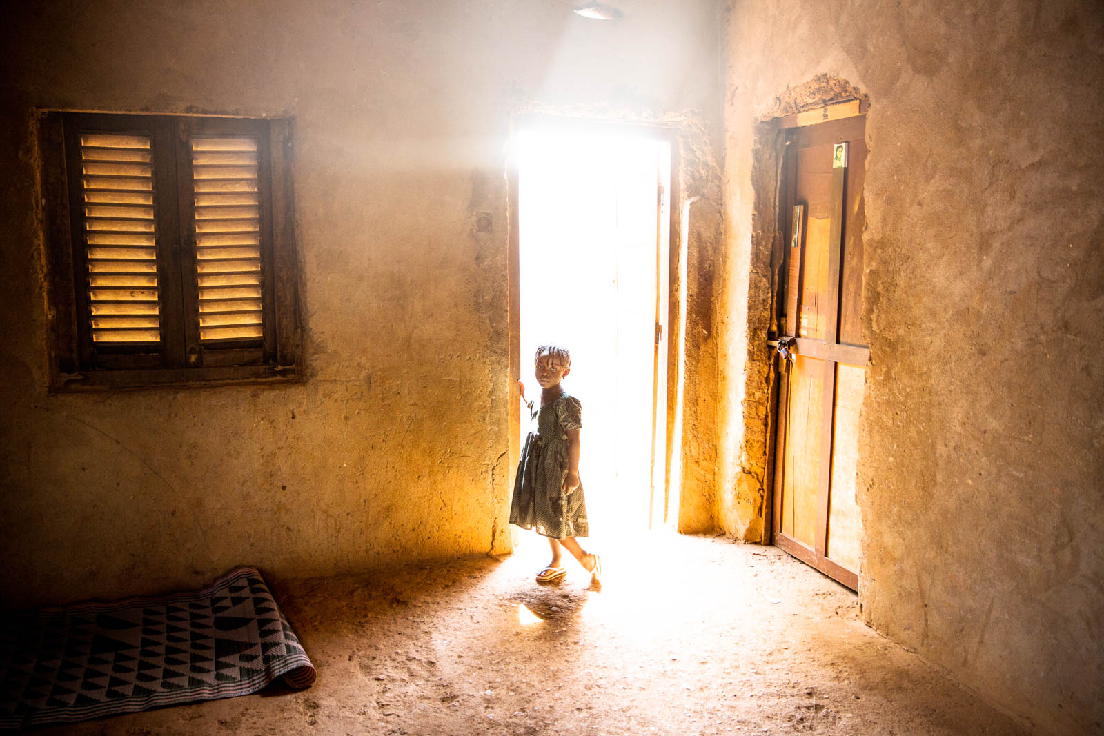 A young girls stands in the doorway of a house. A member of her family, 21 year old Fleuri Doumana, was killed two days earlier by a grenade launched by a member of Seleka. Bangui, Central African Republic.