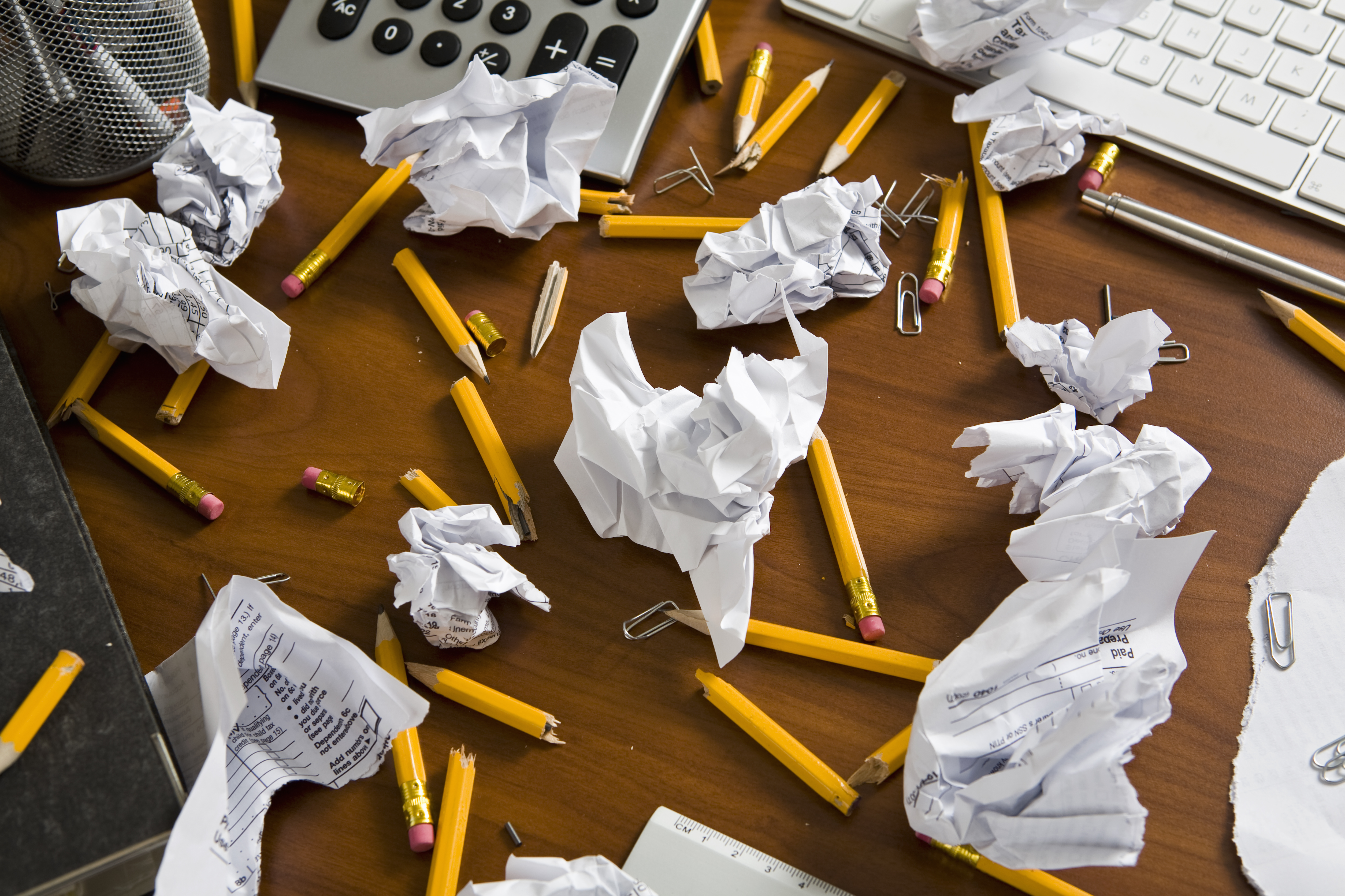 An office desk cluttered with pencils and crumpled paper