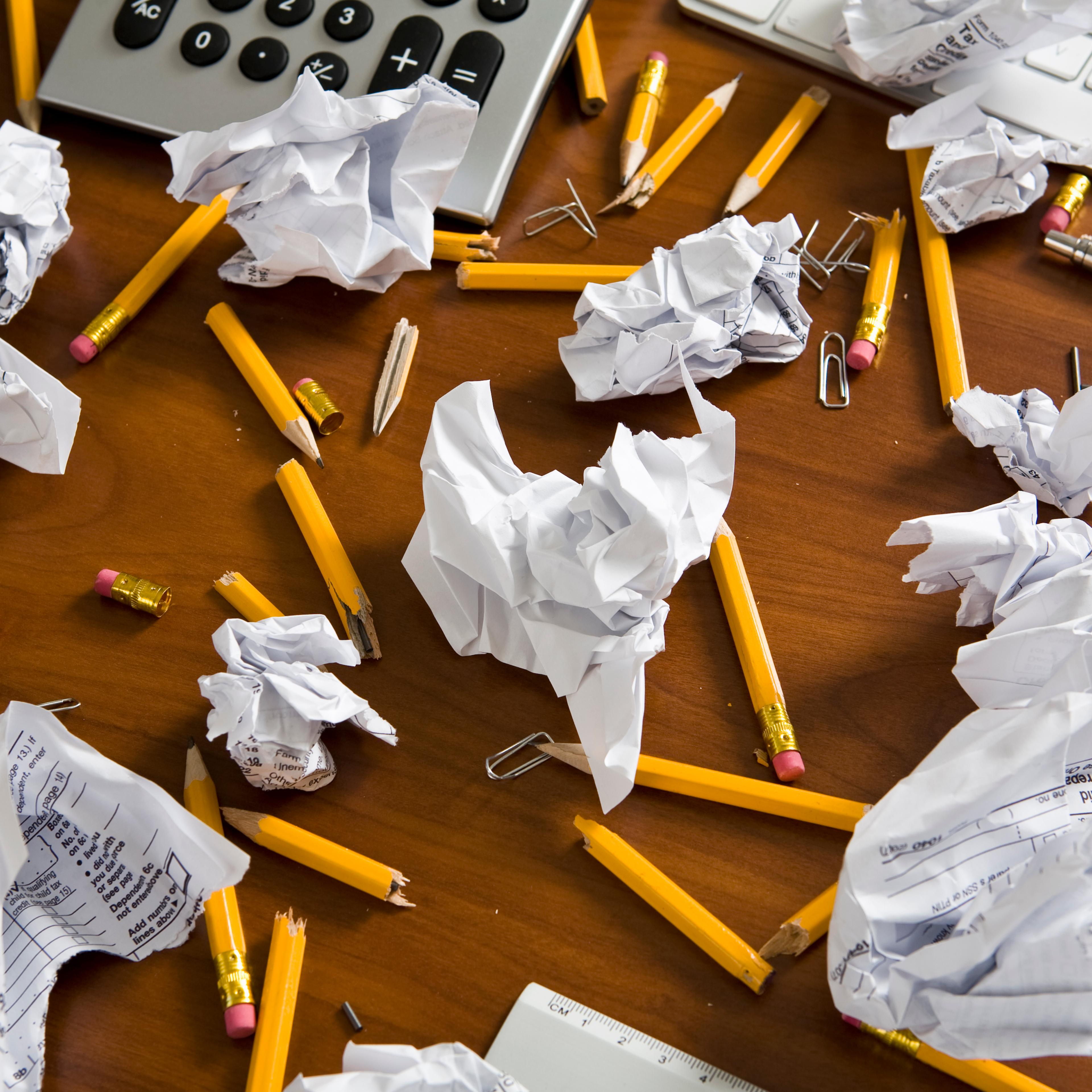 An office desk cluttered with pencils and crumpled paper