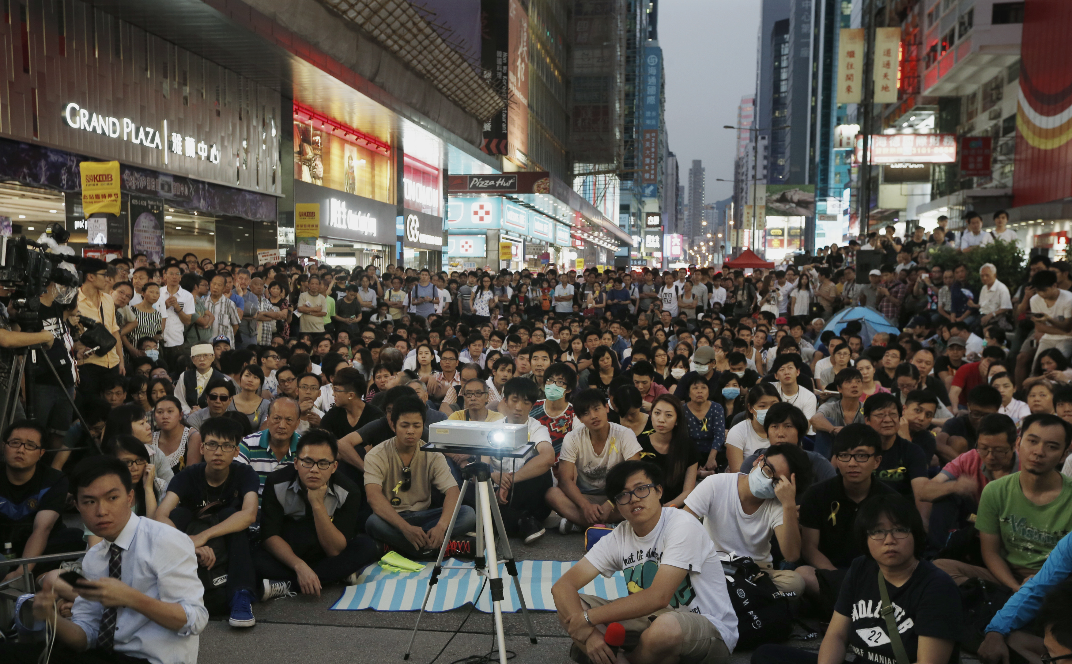 Hundreds of pro-democracy protesters watch a live broadcast of a meeting between student leaders and government officials on a road blocked by them at Mongkok shopping district in Hong Kong