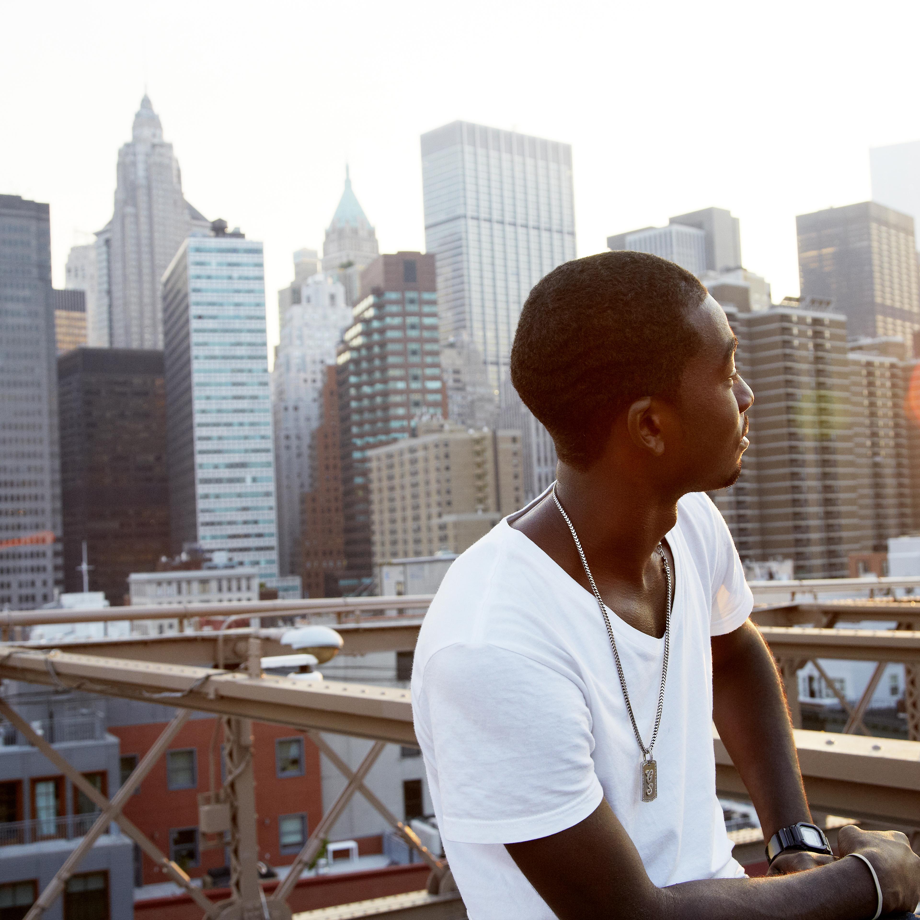 Young man on bridge with city skyline