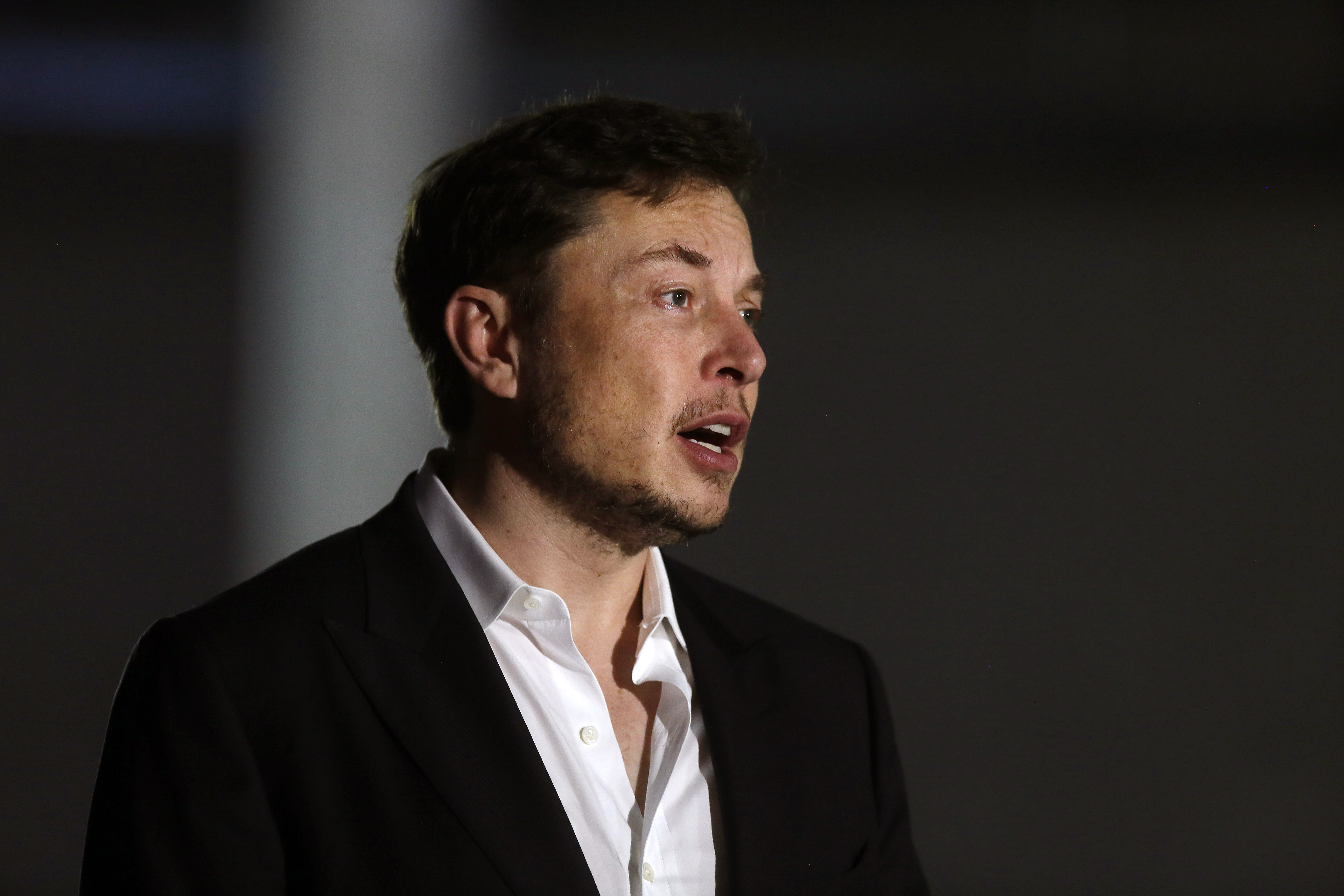 Elon Musk wears a white button down and black blazer