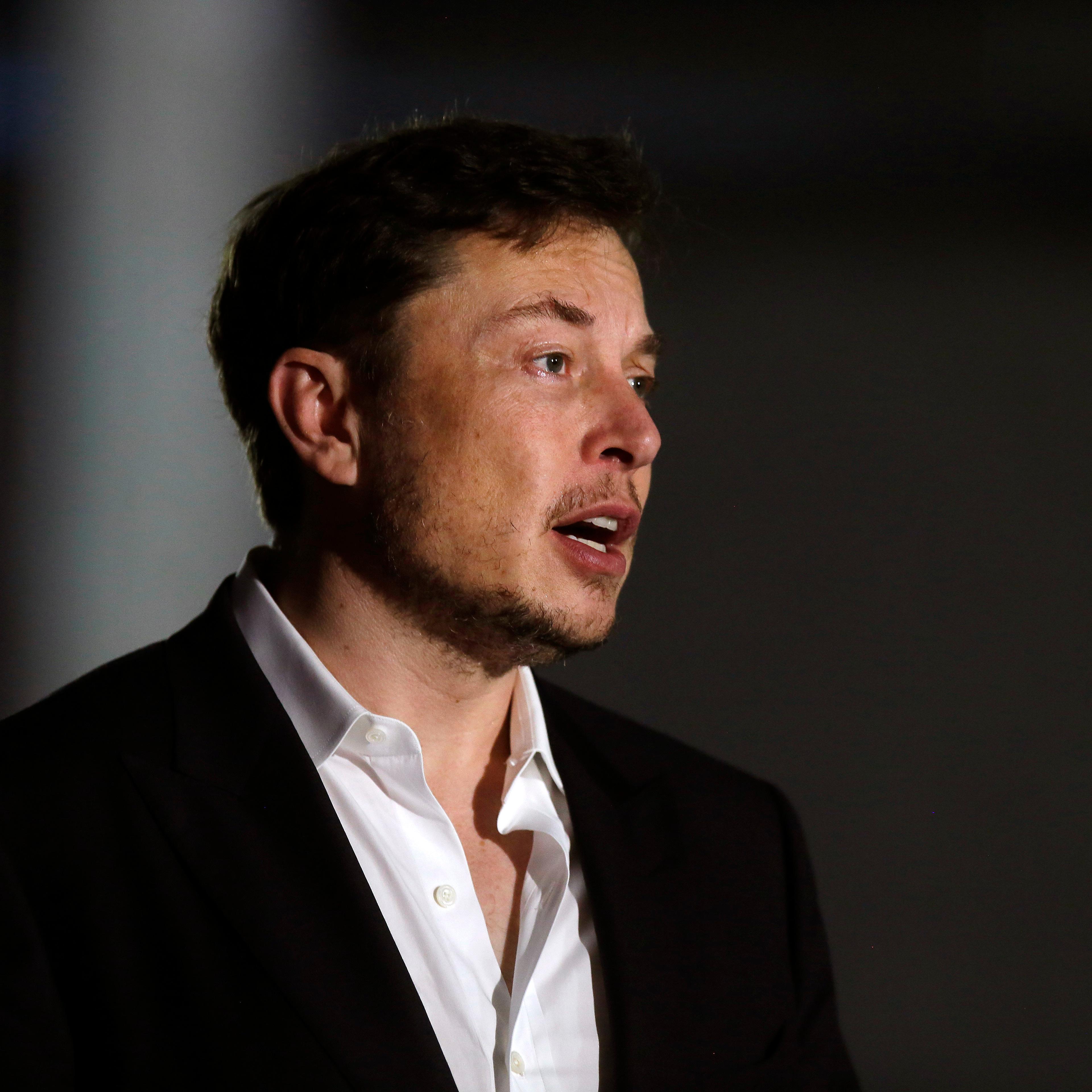 Elon Musk wears a white button down and black blazer