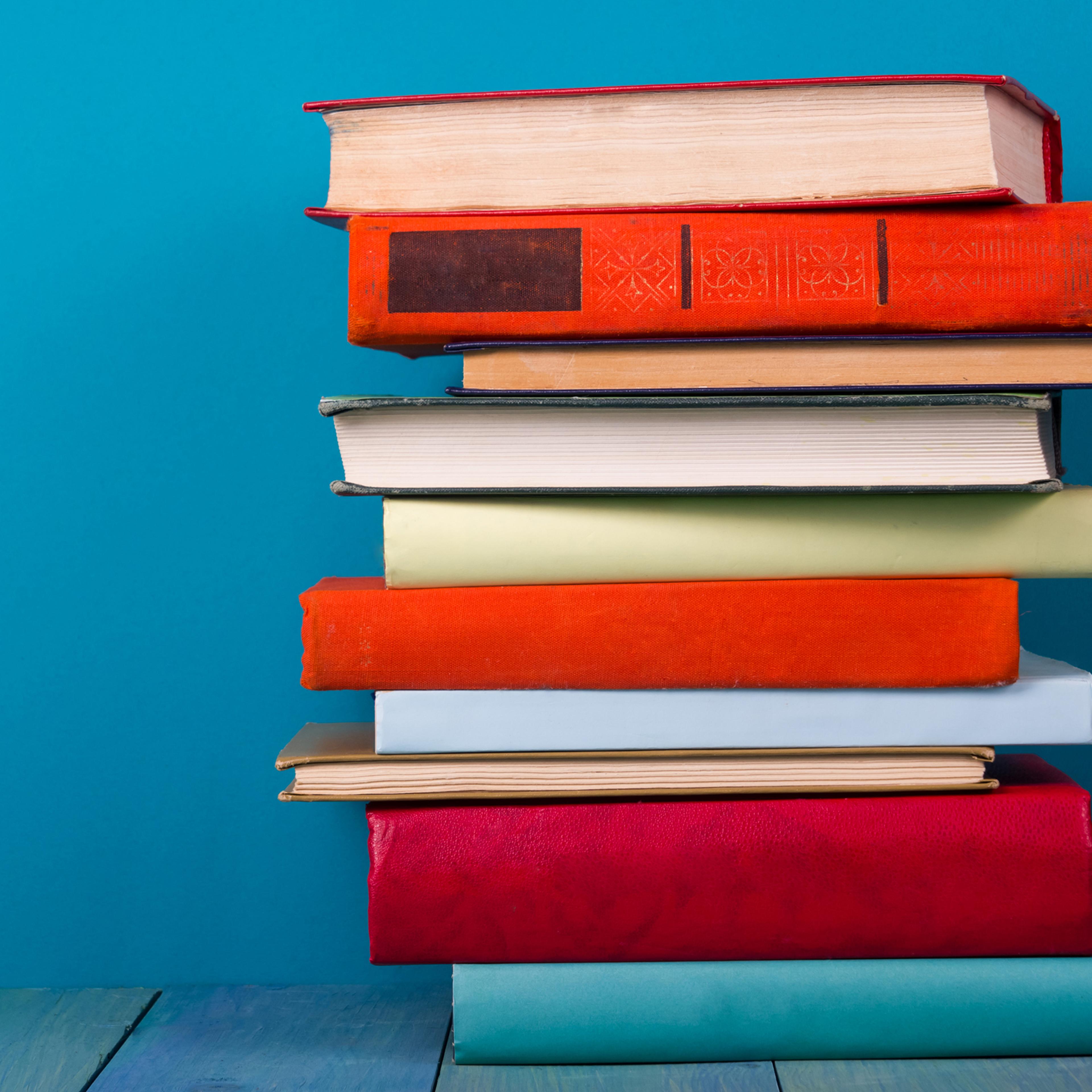 Stack of colorful books, grungy blue background, free copy space