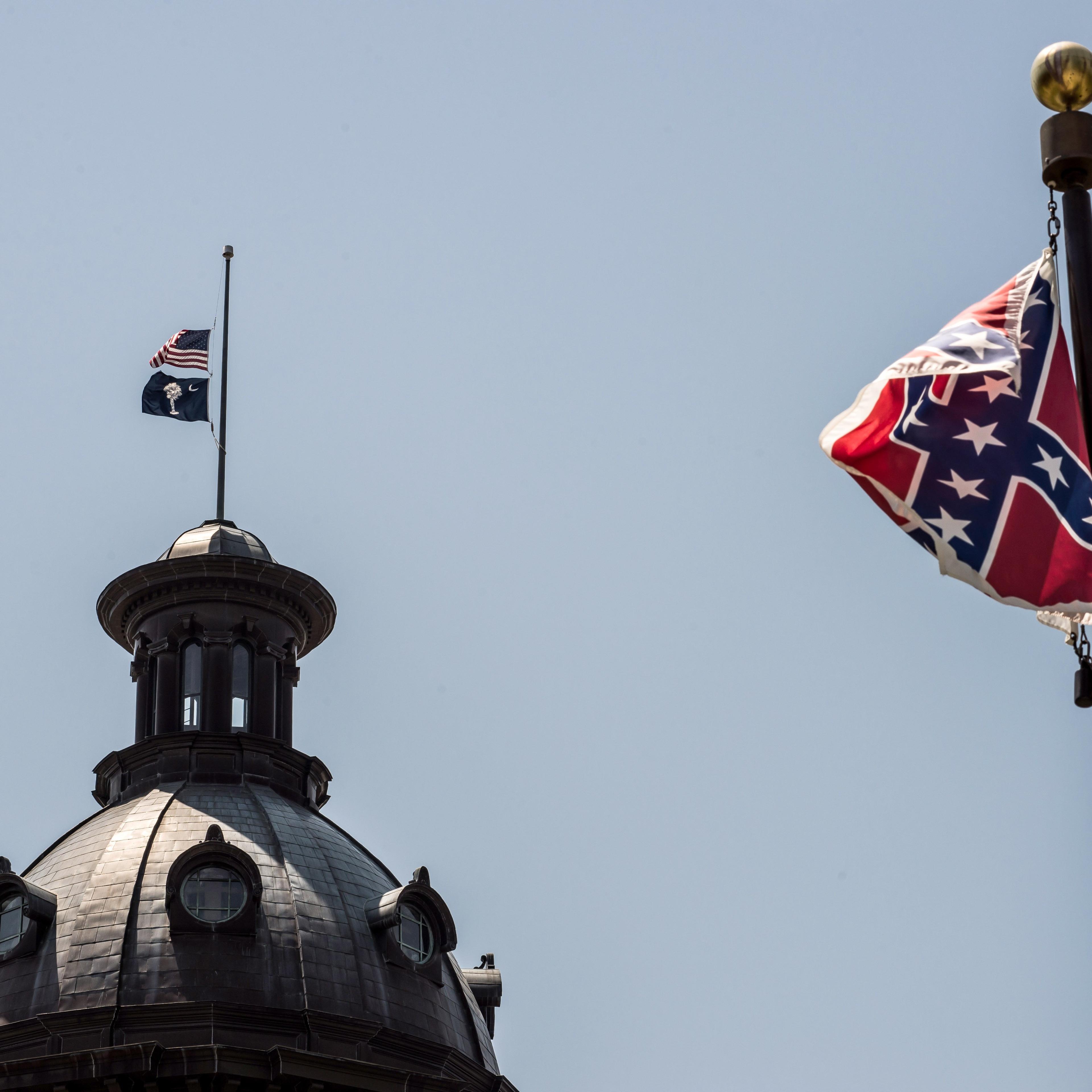 The South Carolina and American flags fly at half mast as the Confederate flag unfurls below at the Confederate Monument June 18, 2015 in Columbia, South Carolina.