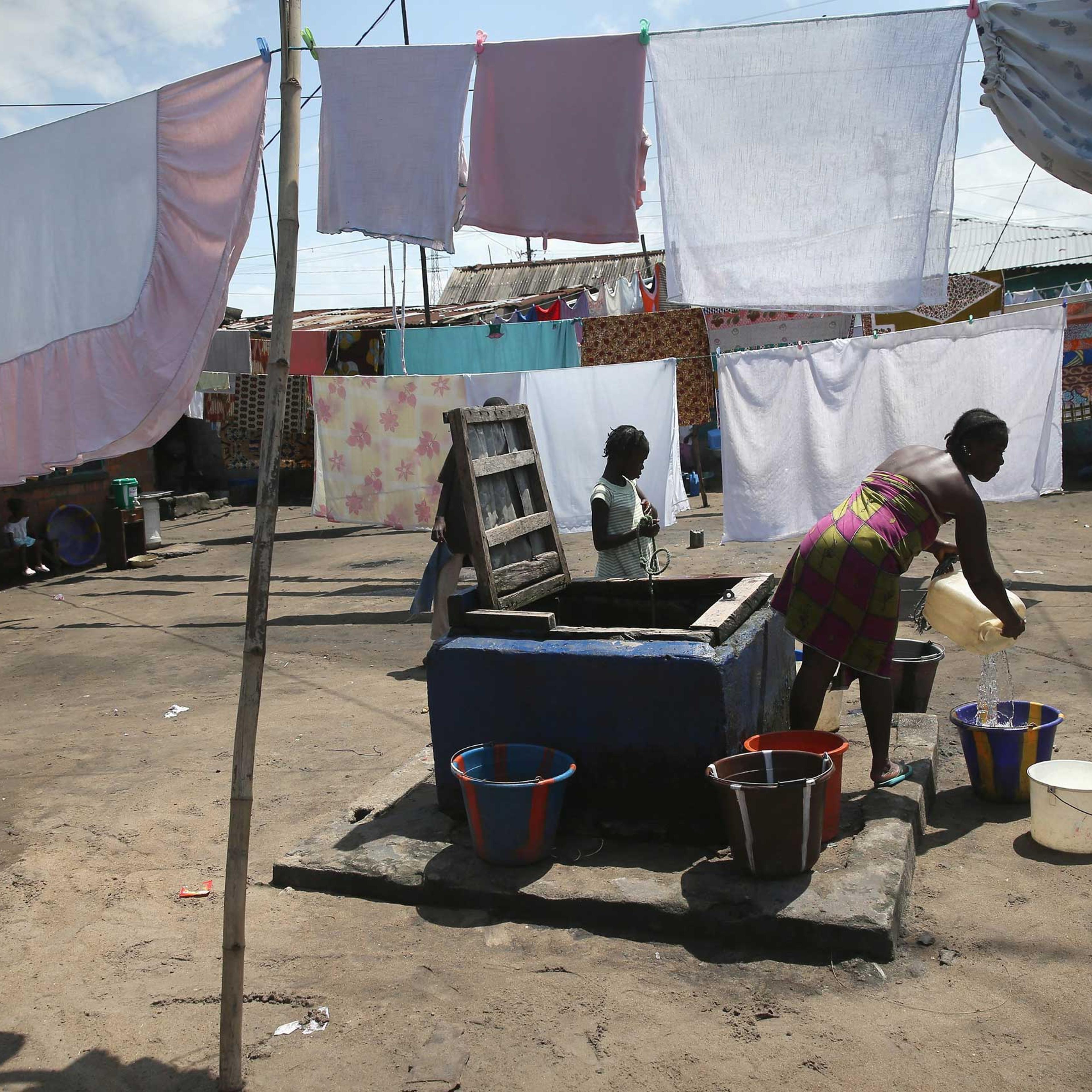 People draw water in the West Point neighborhood, where many people have died from Ebola, in Monrovia, Liberia on Oct. 17, 2014.