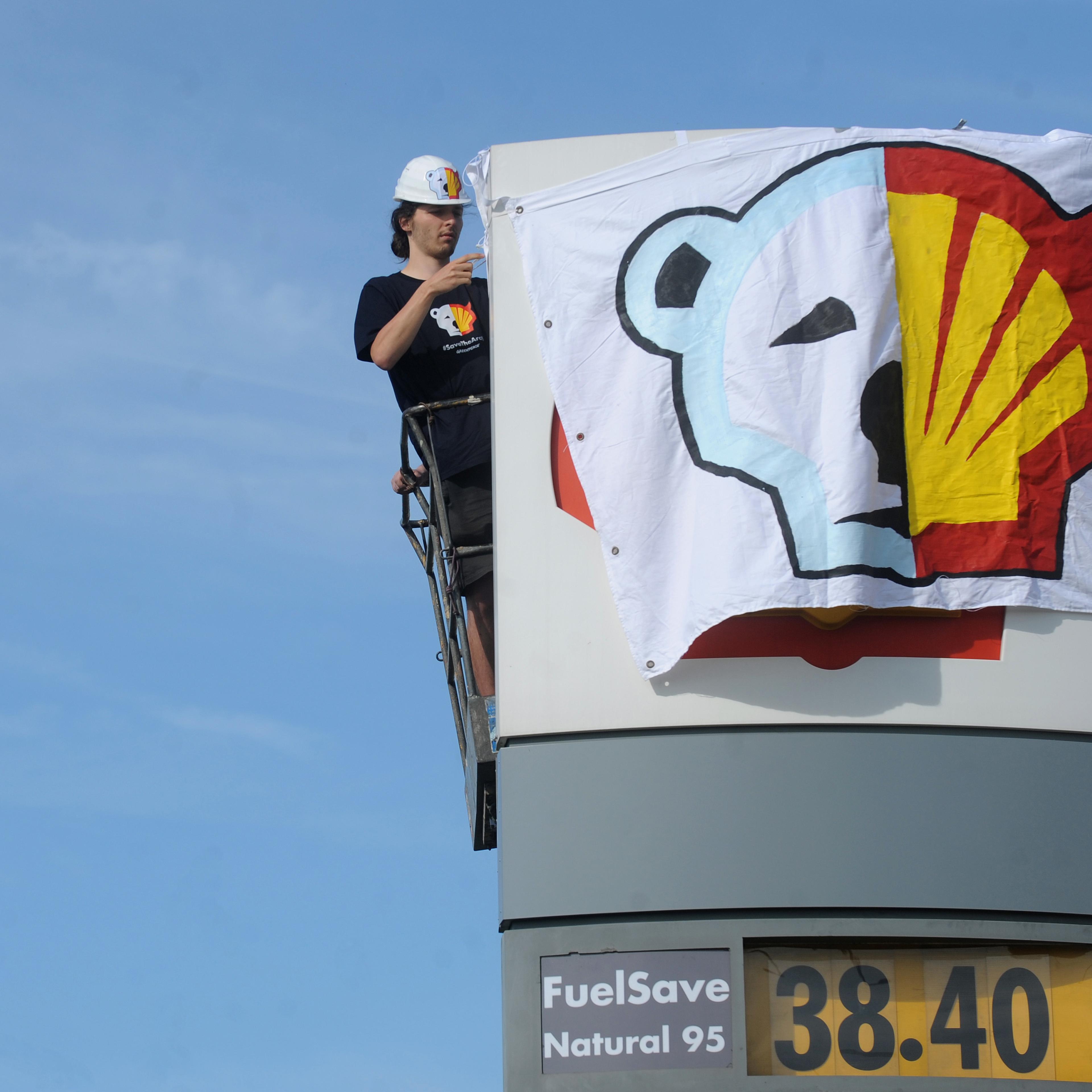 A Greenpeace activist covers the logo of