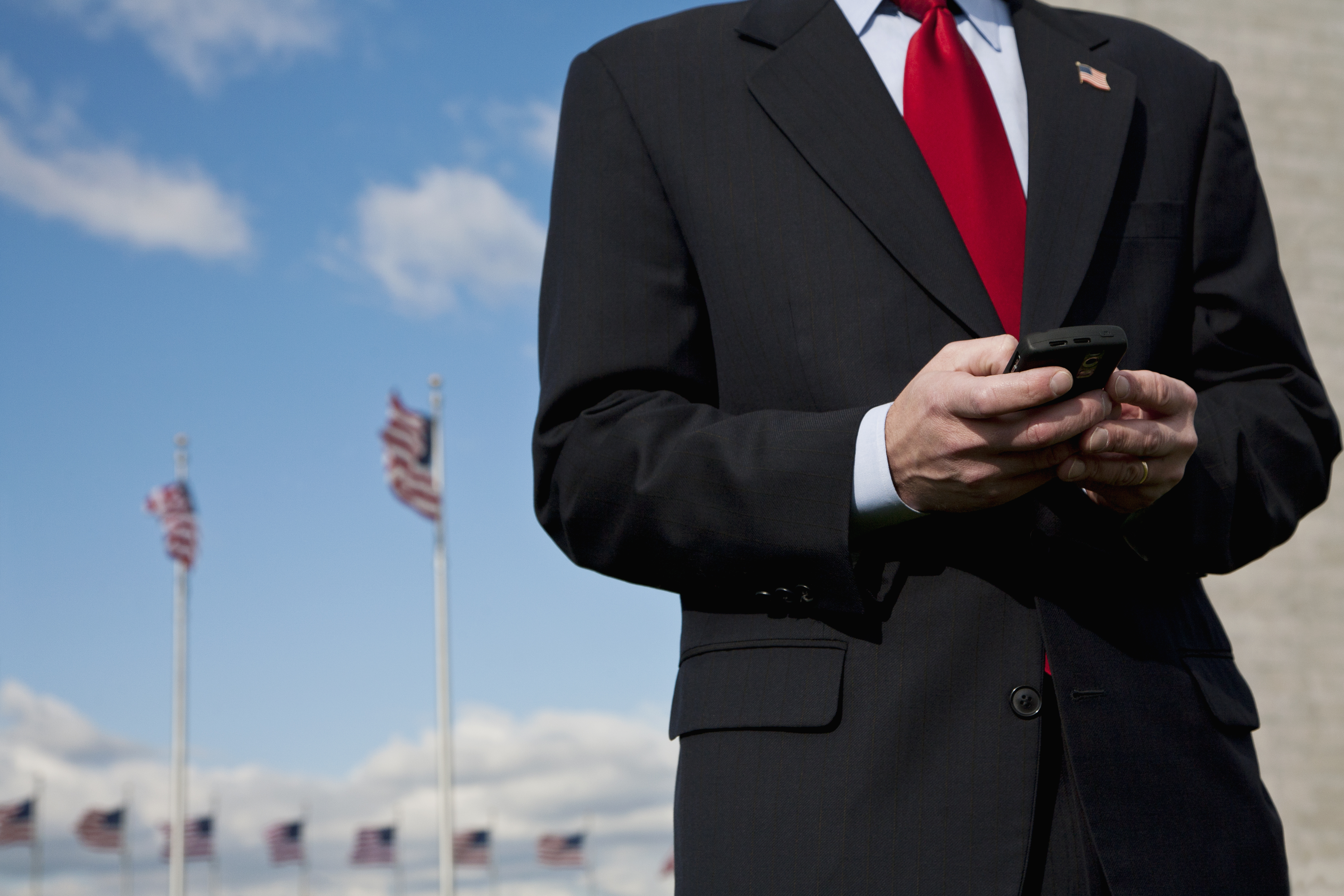 A man text messaging, American flags in the background