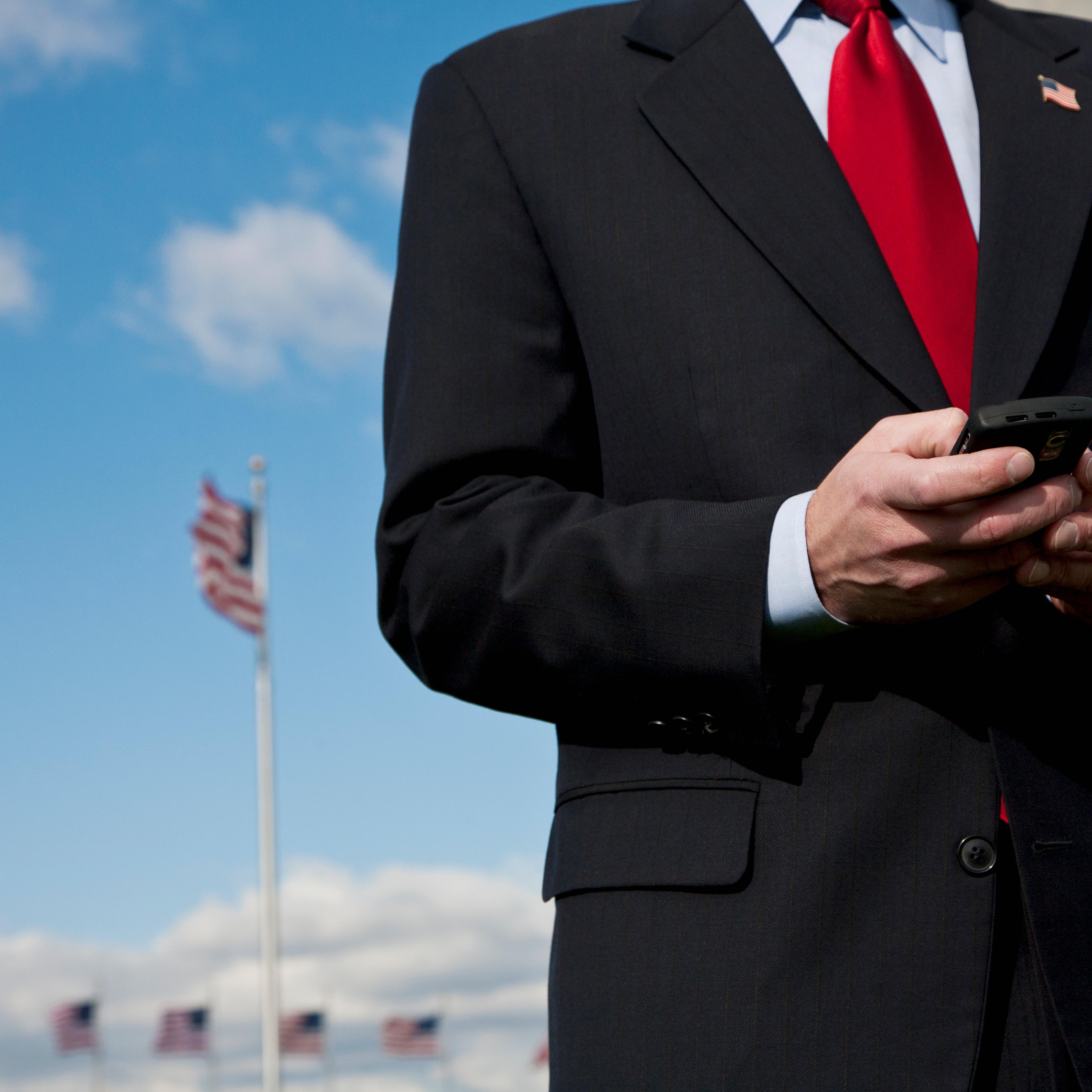 A man text messaging, American flags in the background
