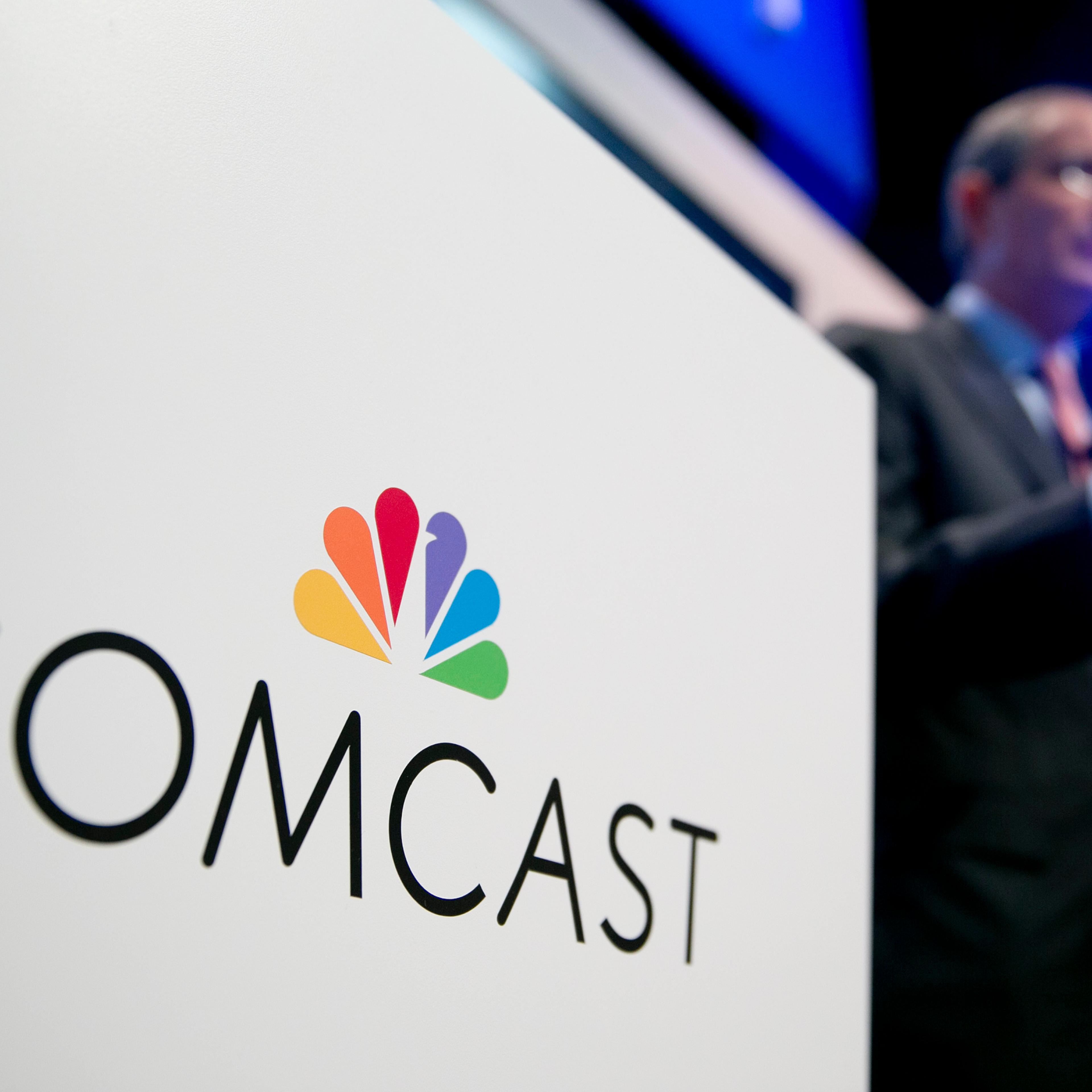 The Comcast Corp. logo is seen as Brian Roberts, chairman and chief executive officer of Comcast Corp., right, speaks during a news conference at the National Cable and Telecommunications Association (NCTA) Cable Show in Washington, D.C., U.S., on Tuesda