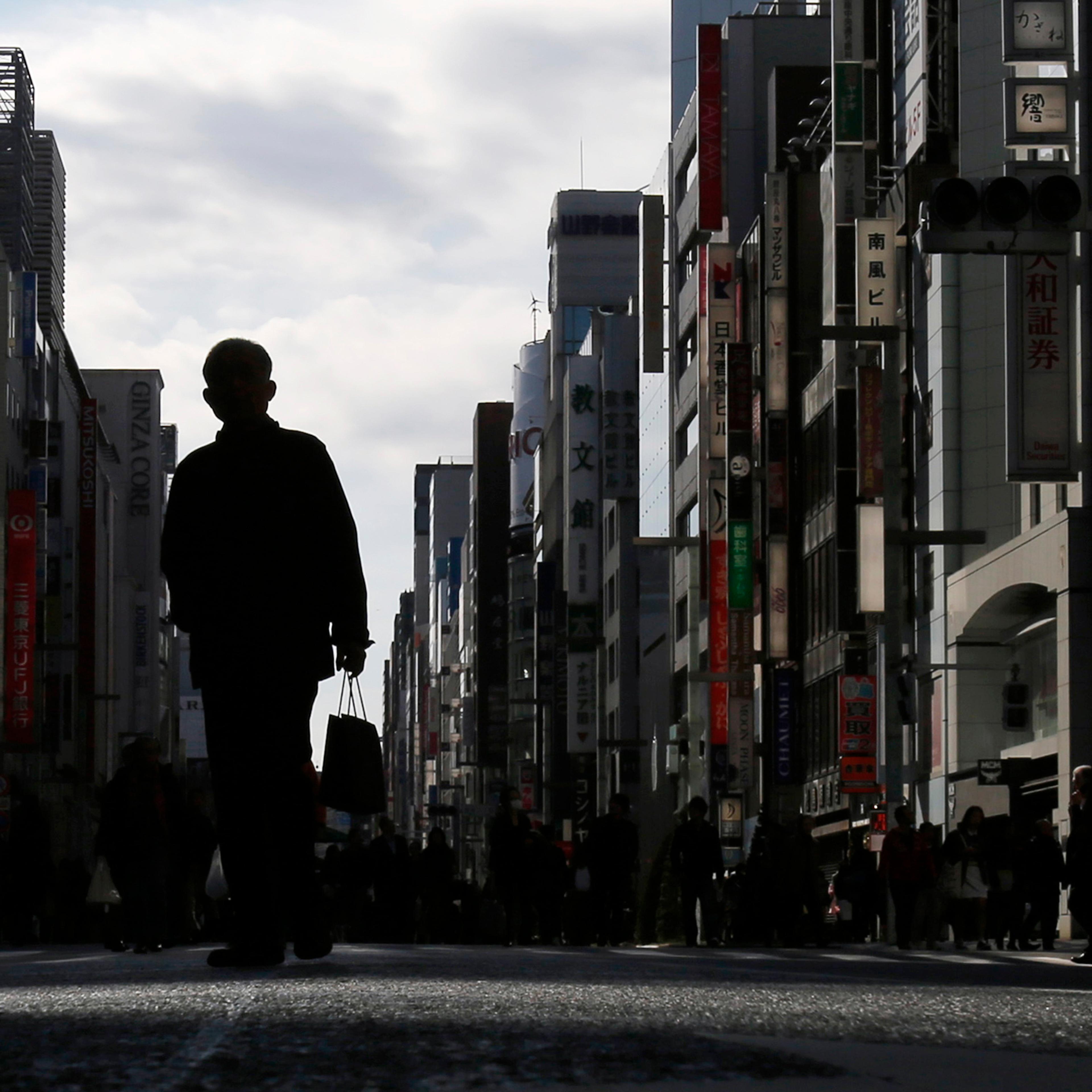 A man holding a shopping bag walks on a street at Tokyo's Ginza shopping district