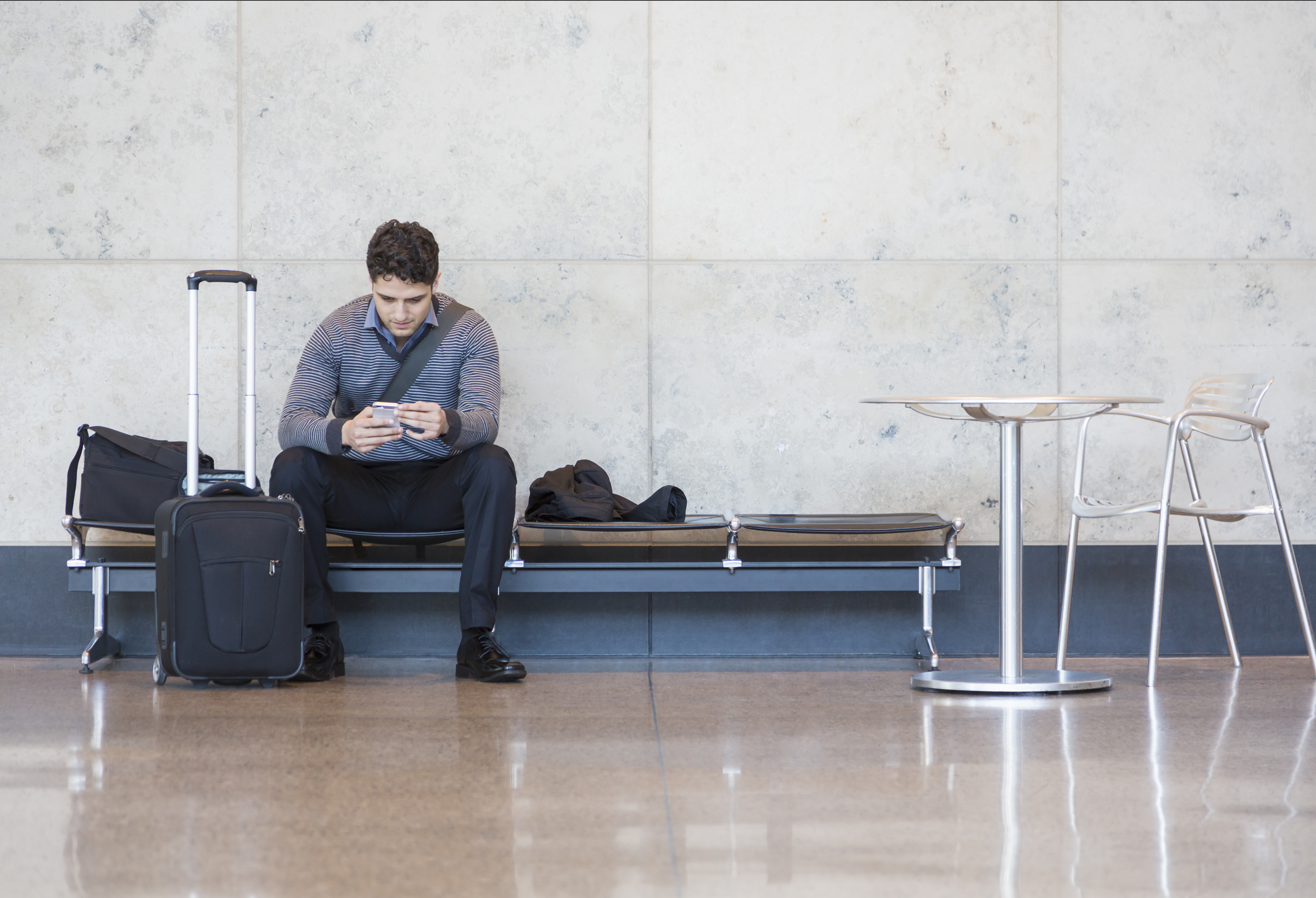 Male business traveler with cell phone in airport