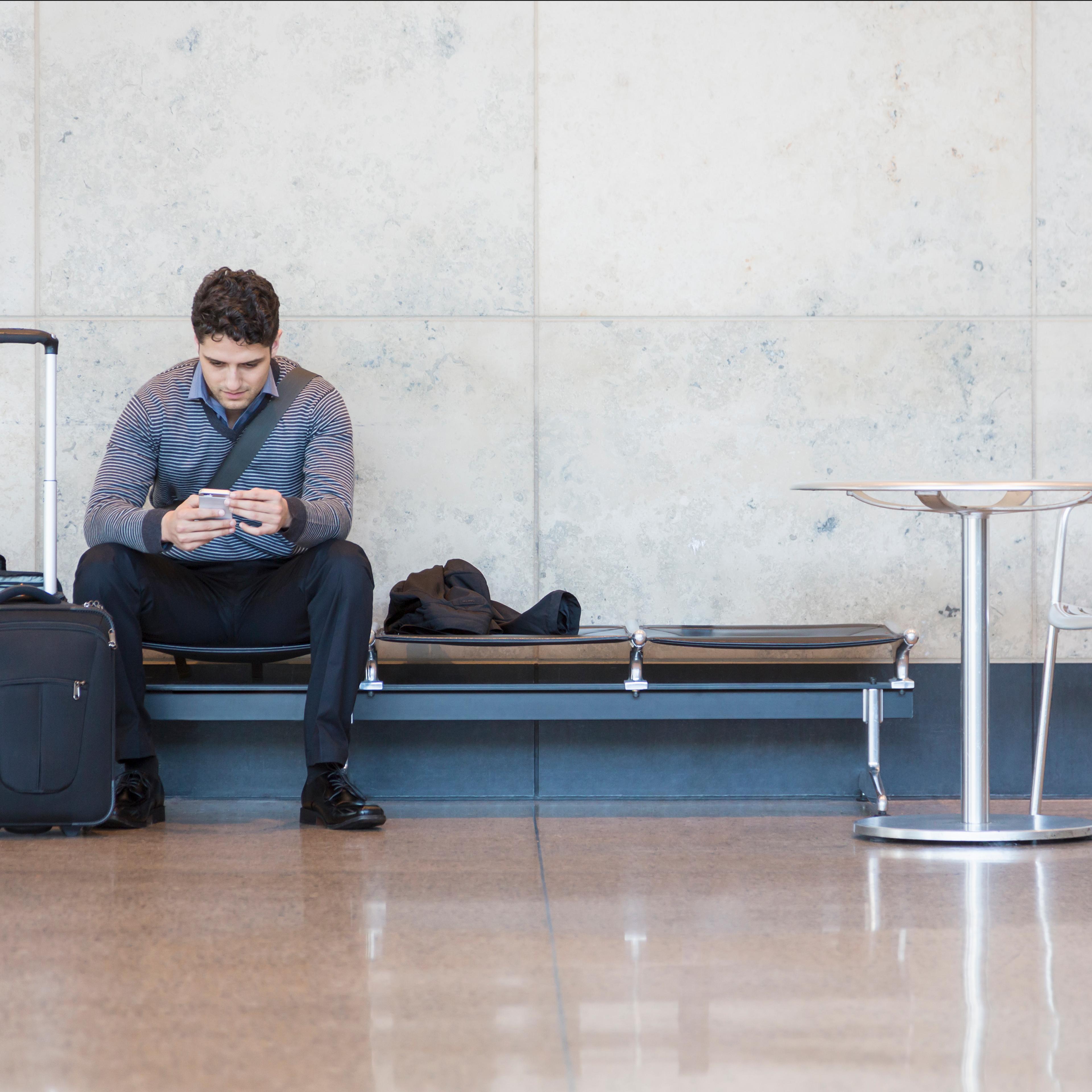 Male business traveler with cell phone in airport