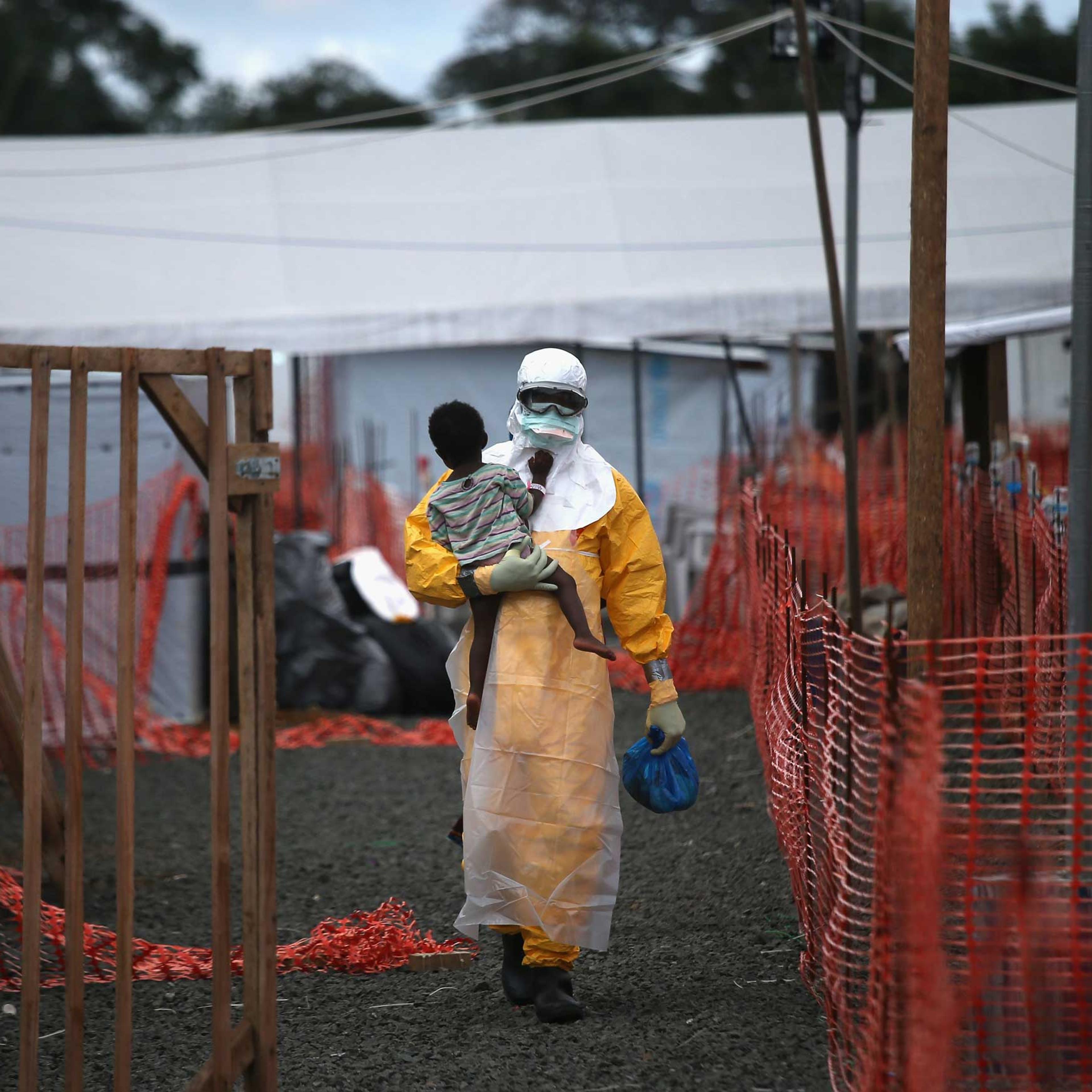 A Doctors Without Borders health worker in protective clothing carries a child suspected of having Ebola in the MSF treatment center on Oct. 5, 2014 in Paynesville, Liberia.