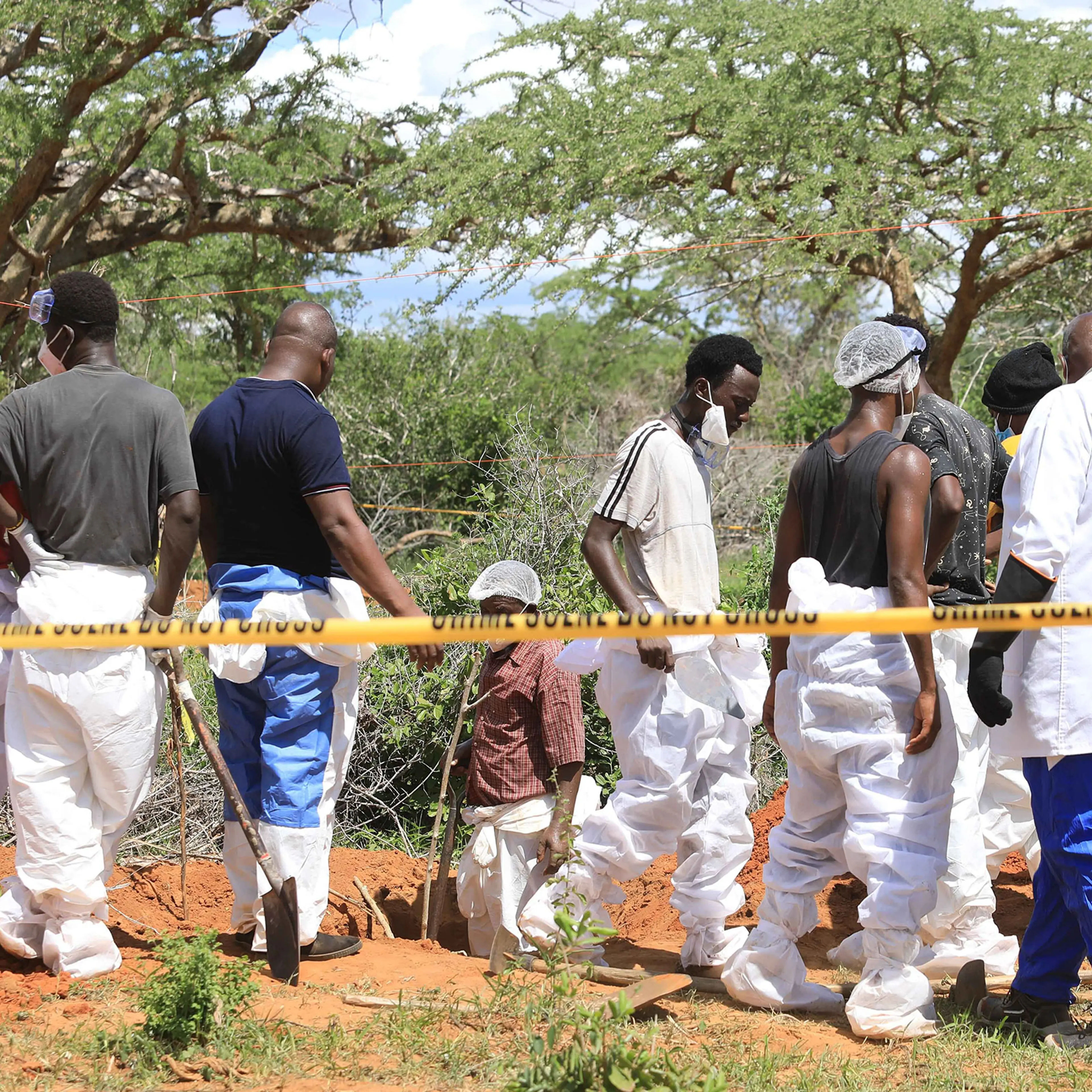 Officials inspect a forest where bodies were found near the Good News International Church