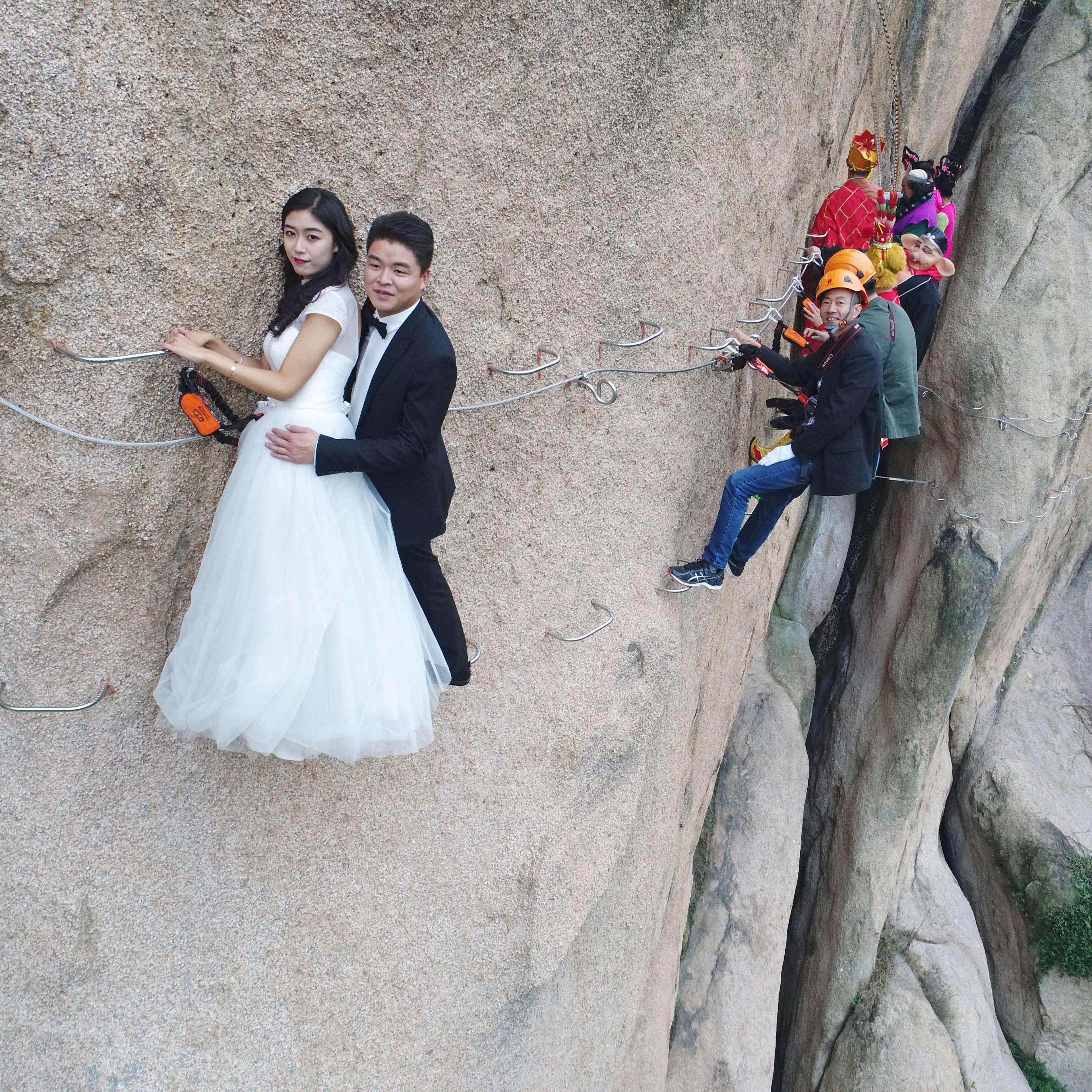 Newlywed Couple Poses For Wedding Photos On Cliff Face In Zhumadian