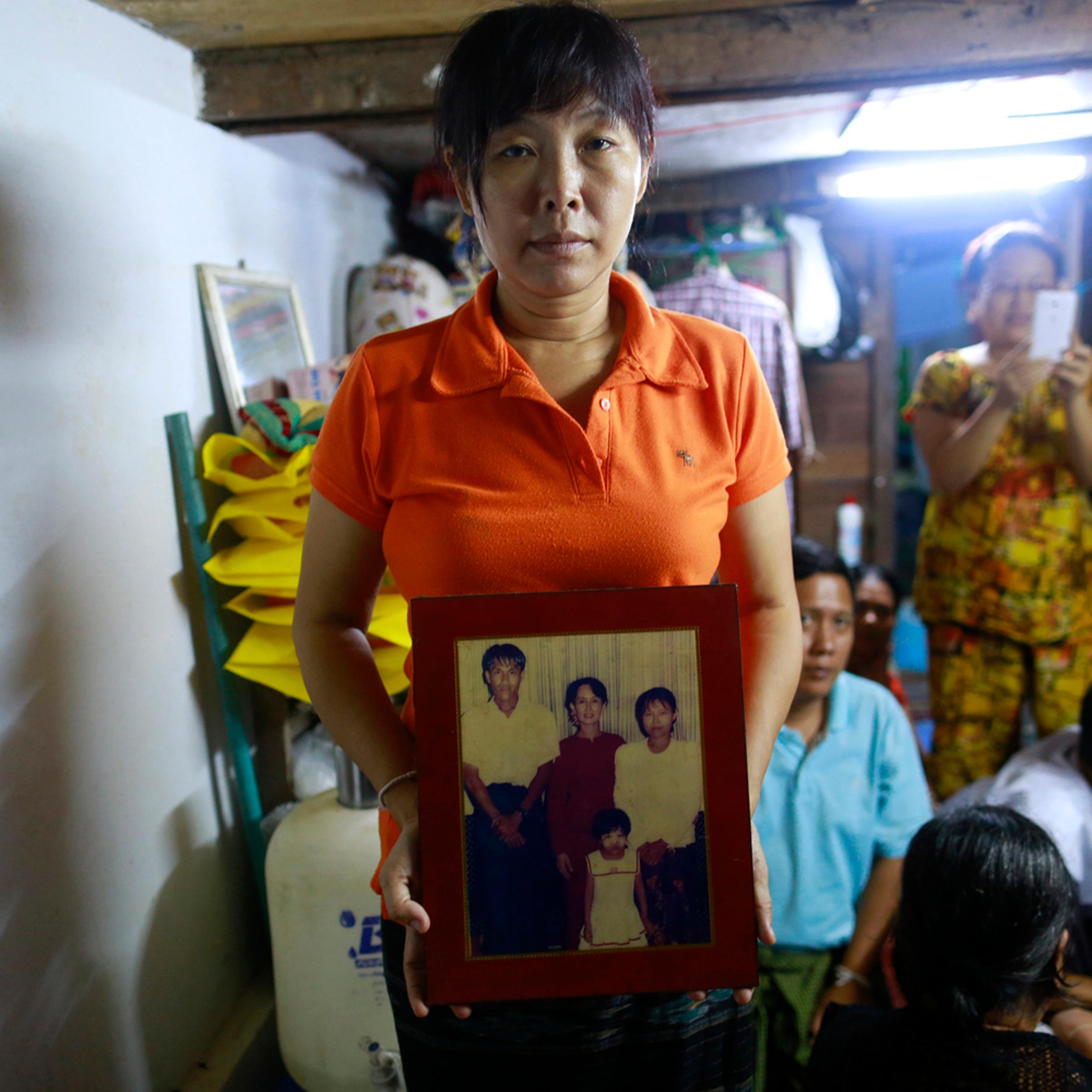 Than Dar, the wife of slain journalist Par Gyi, holds a family photograph showing herself, her husband and daughter posing with Aung San Suu Kyi at their home, in Yangon