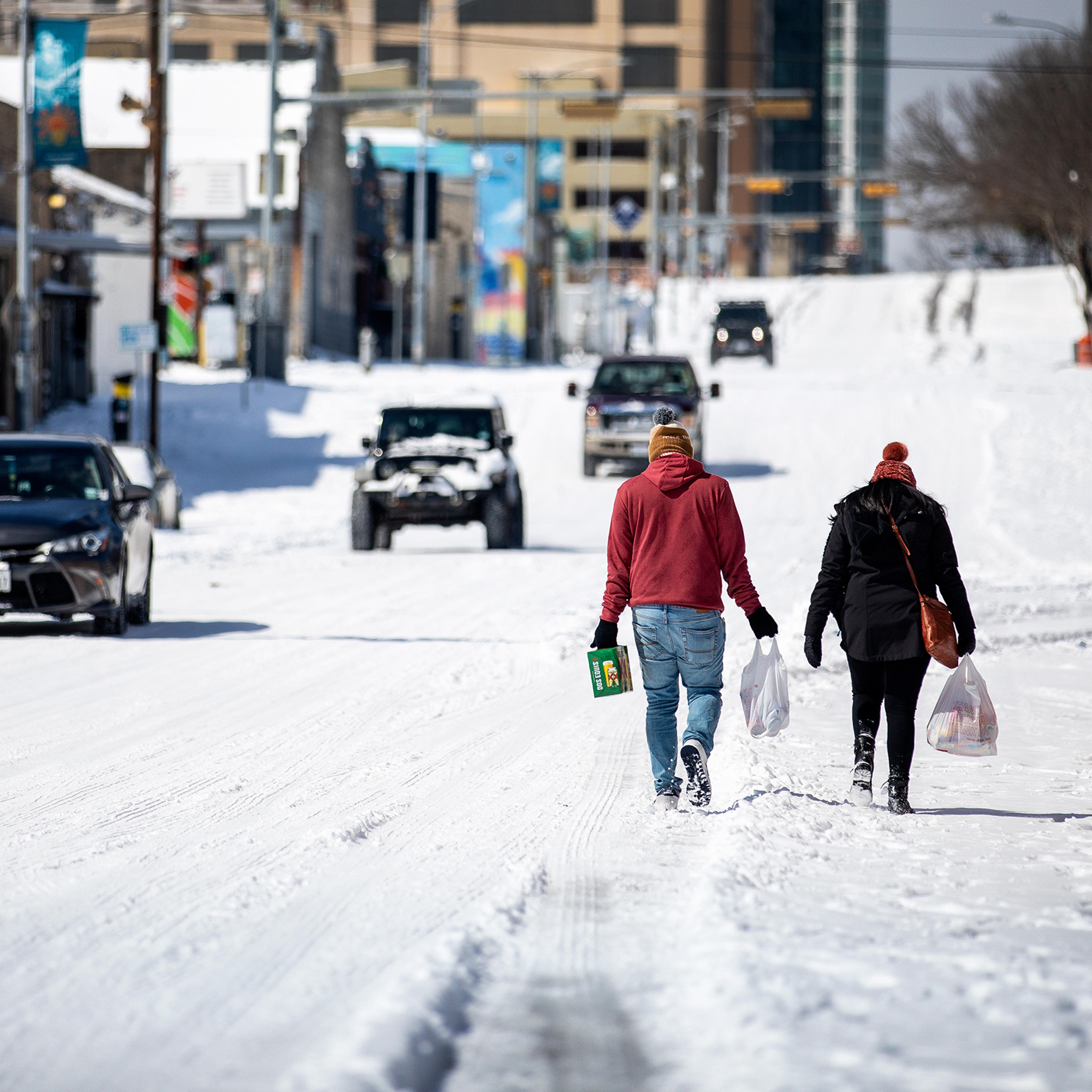 People carry groceries on Feb. 15 in Austin after a winter storm brought historic cold weather to Texas